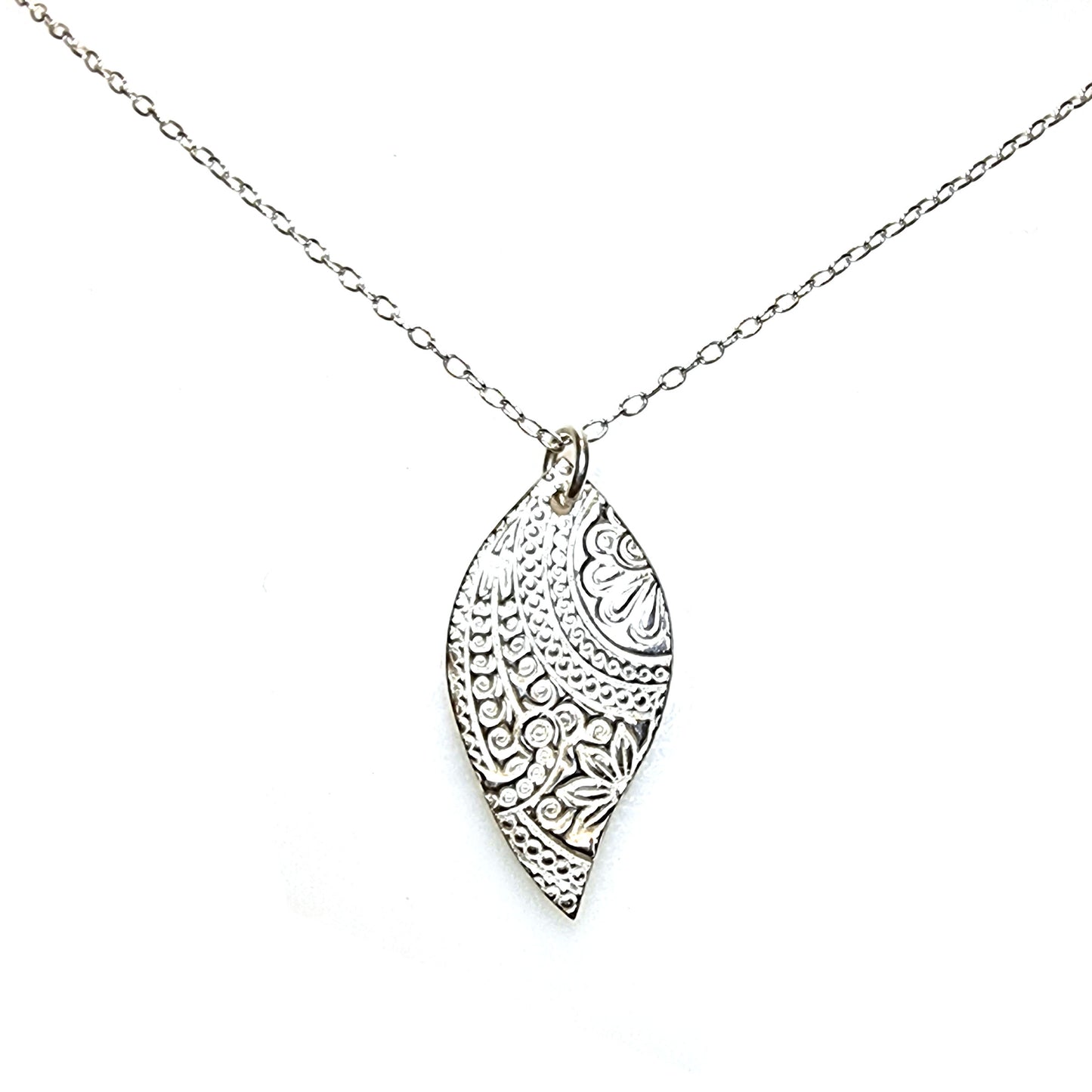 A silver asymmetric patterned leaf-shaped pendant on a chain