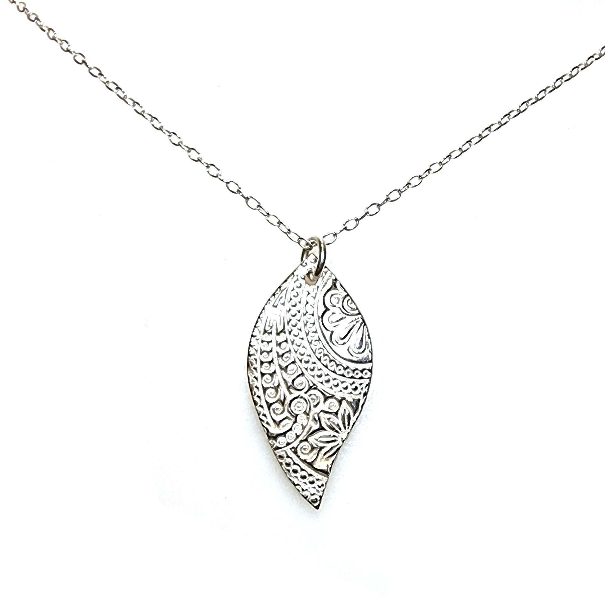A silver asymmetric patterned leaf-shaped pendant on a chain