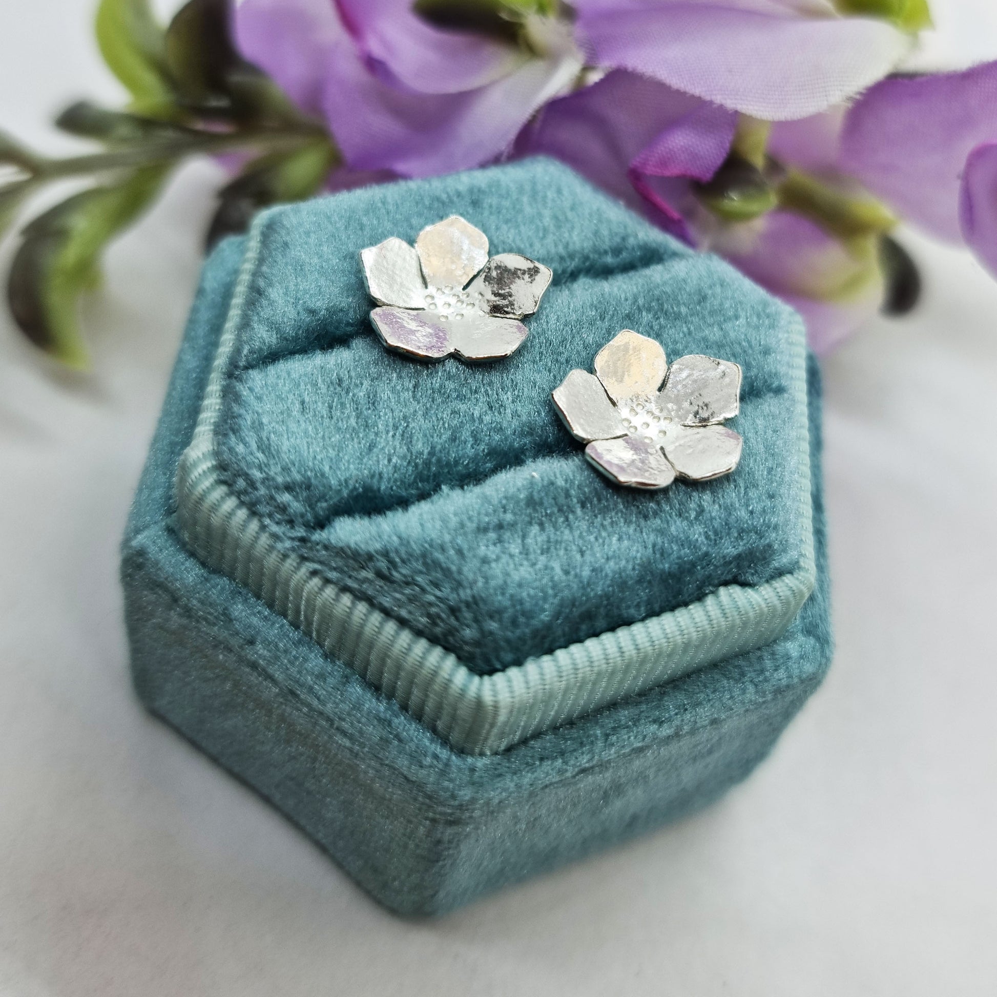 Silver five petal flower stud earrings in box with flowers