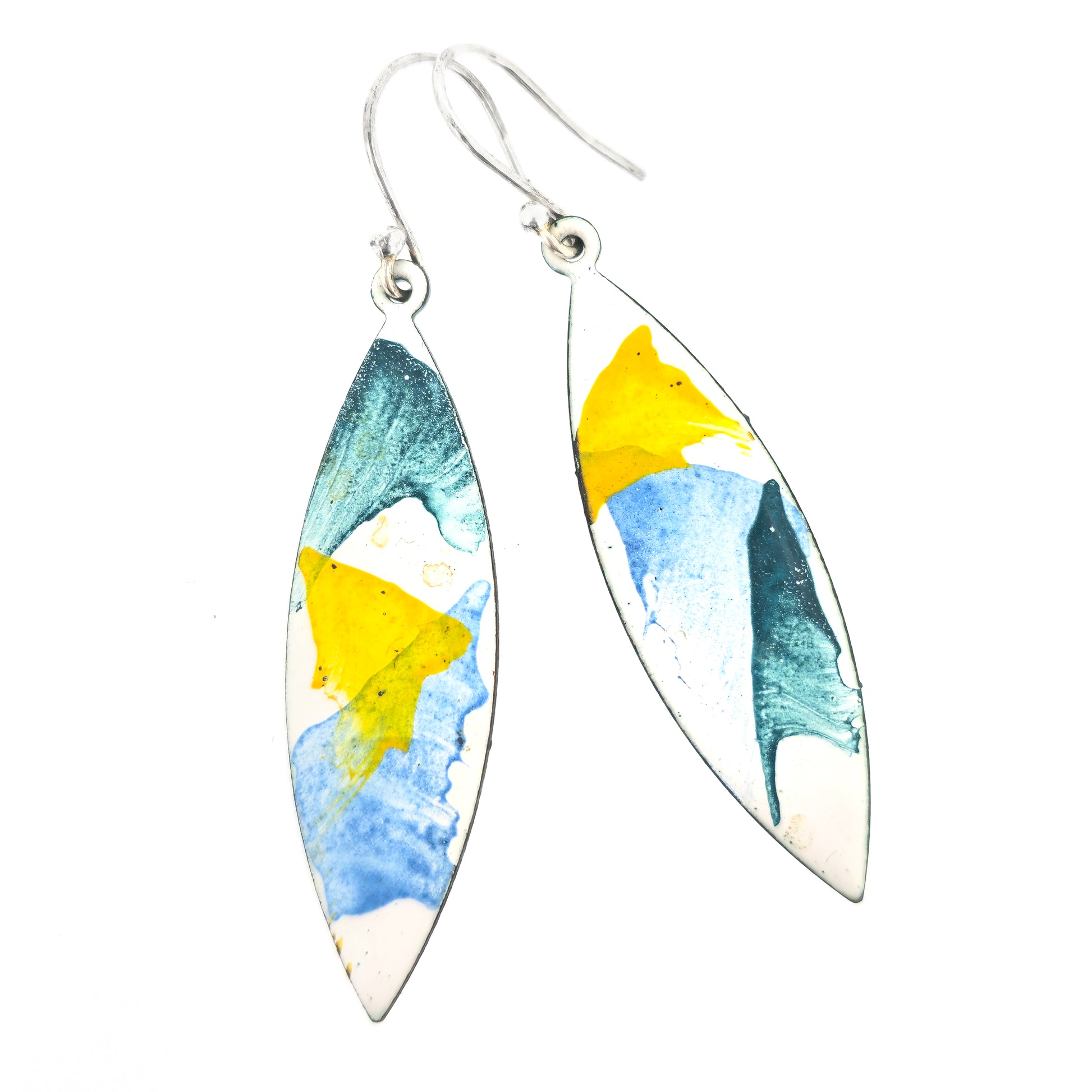 Boat shaped shaped enamel drop earrings with green, blue and yellow splashes on a white background. On silver ear hooks.