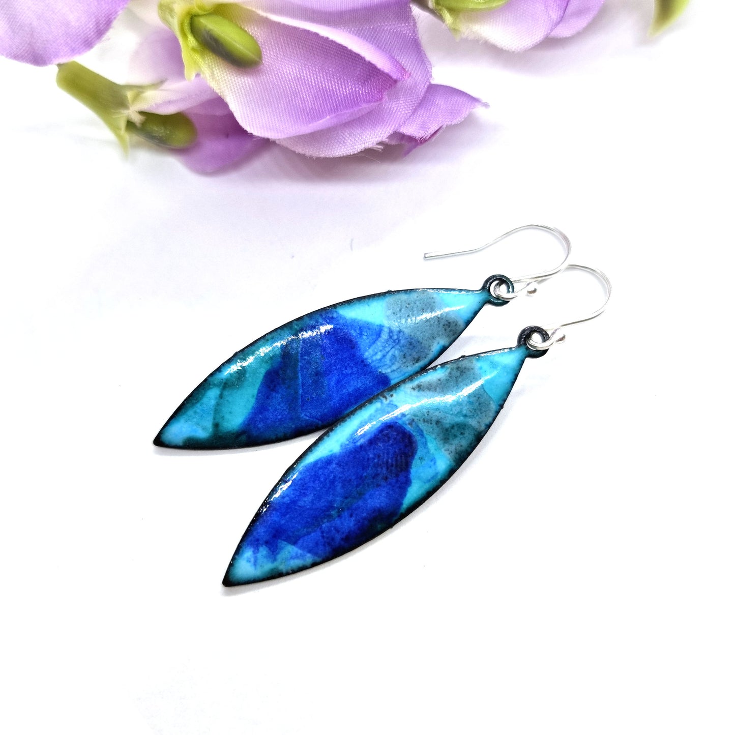 Navette shaped blue enamel drop earrings with splashes of grey and dark blue with flowers.