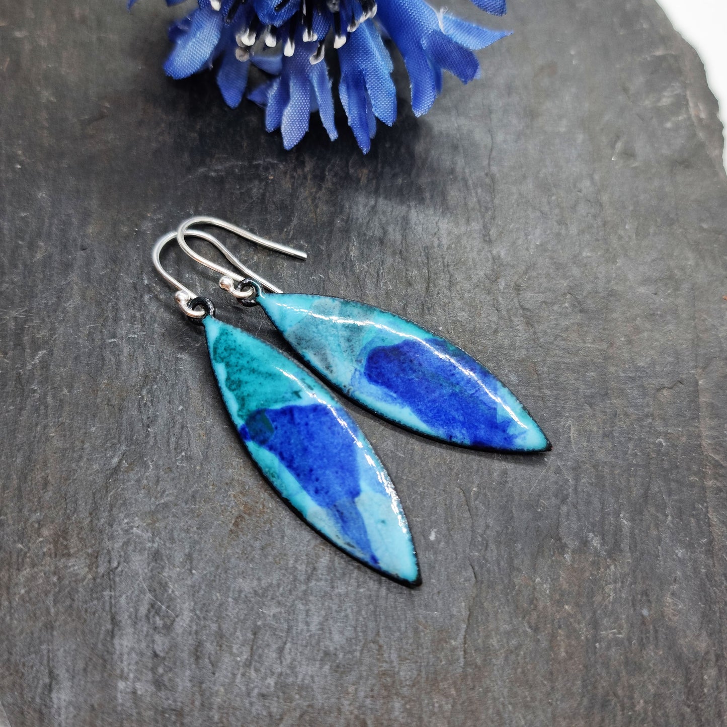 Navette shaped blue enamel drop earrings with splashes of grey and dark blue with flower