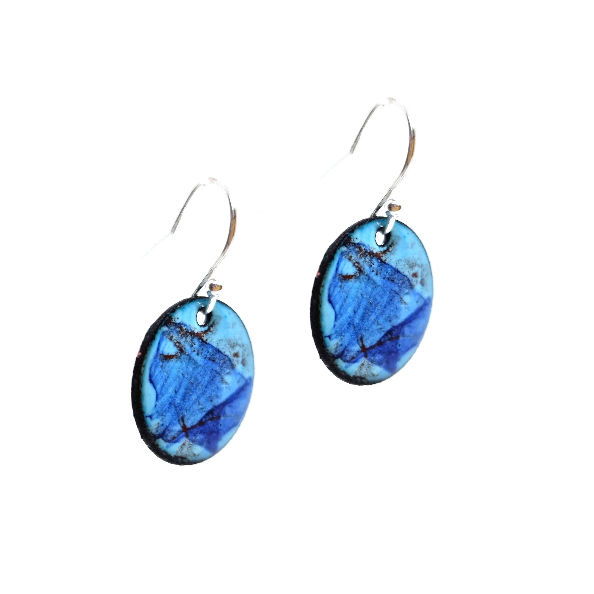 Round enamel drop earrings with splashes of dark blue, grey and red on a light blue background.