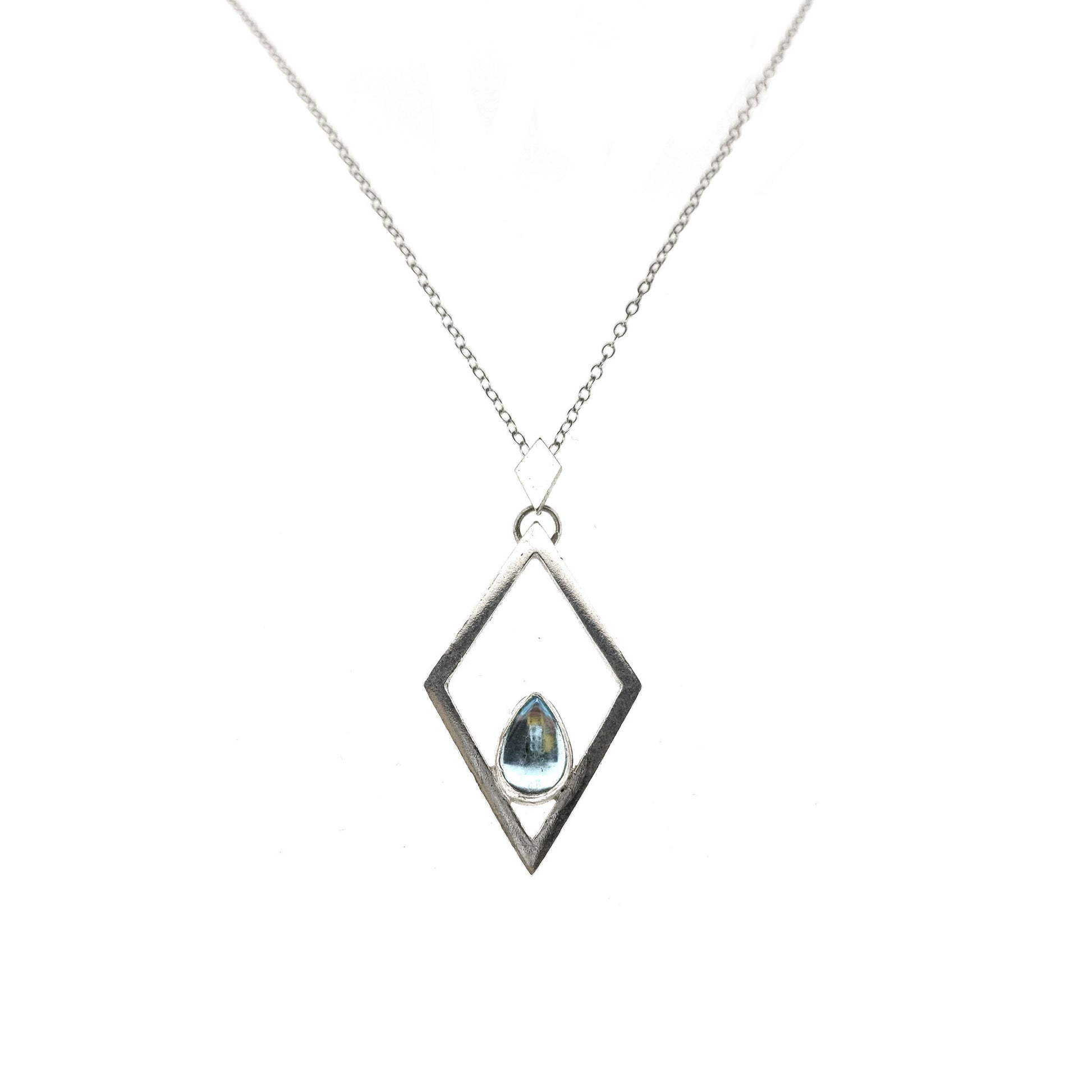 A silver open diamond shaped pendant with a teardrop shaped blue topaz gemstone set inside. A small diamond shaped bail attaches the pendant to a silver chain.