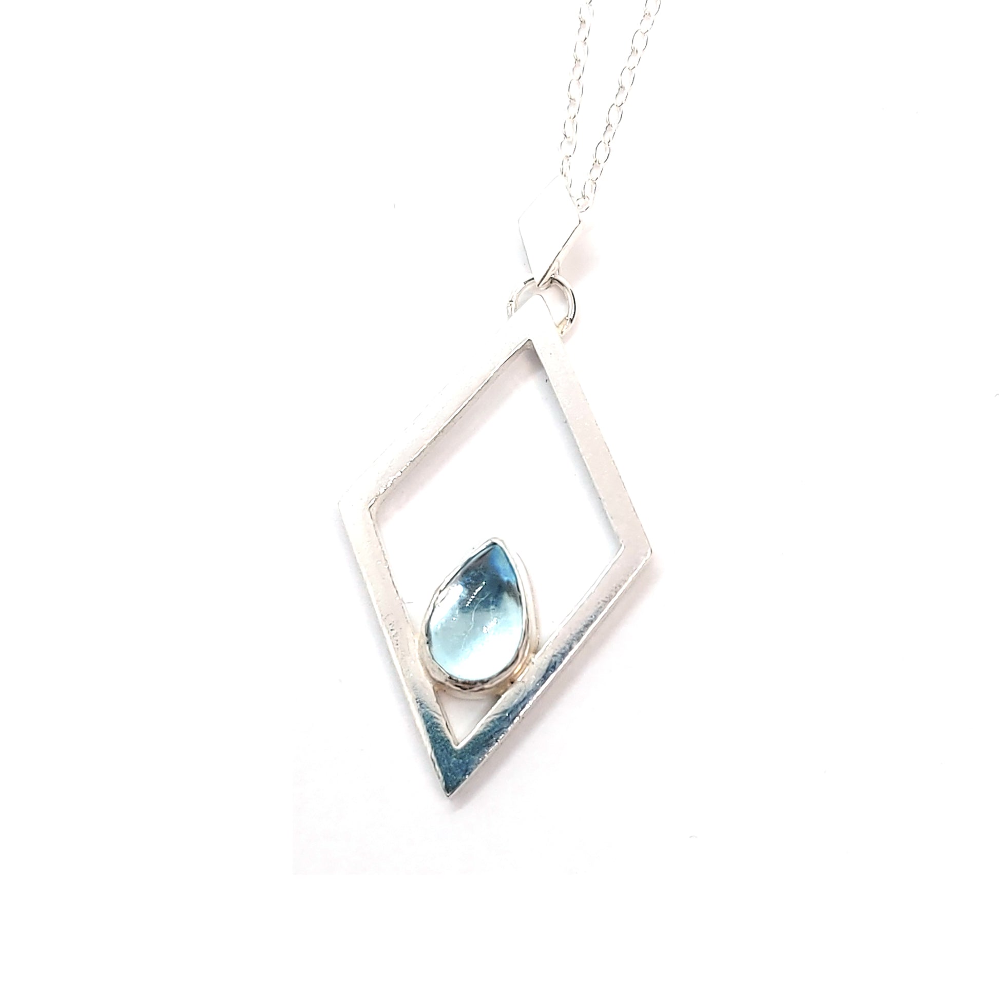 A silver open diamond shaped pendant with a teardrop shaped blue topaz gemstone set inside. A small diamond shaped bail attaches the pendant to a silver chain.