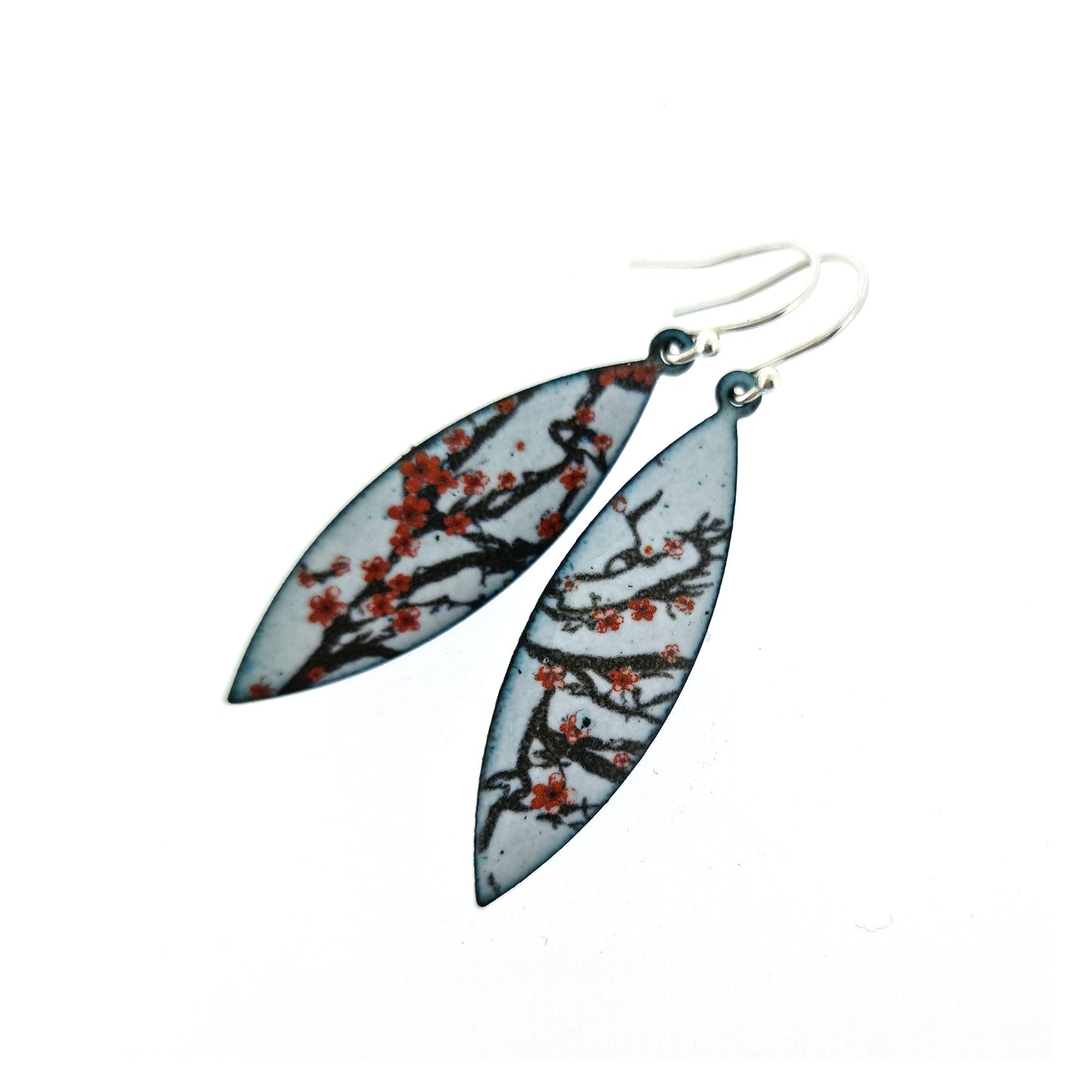 Boat-shaped enamel drop earrings with branches of red cherry blossom on a grey background.