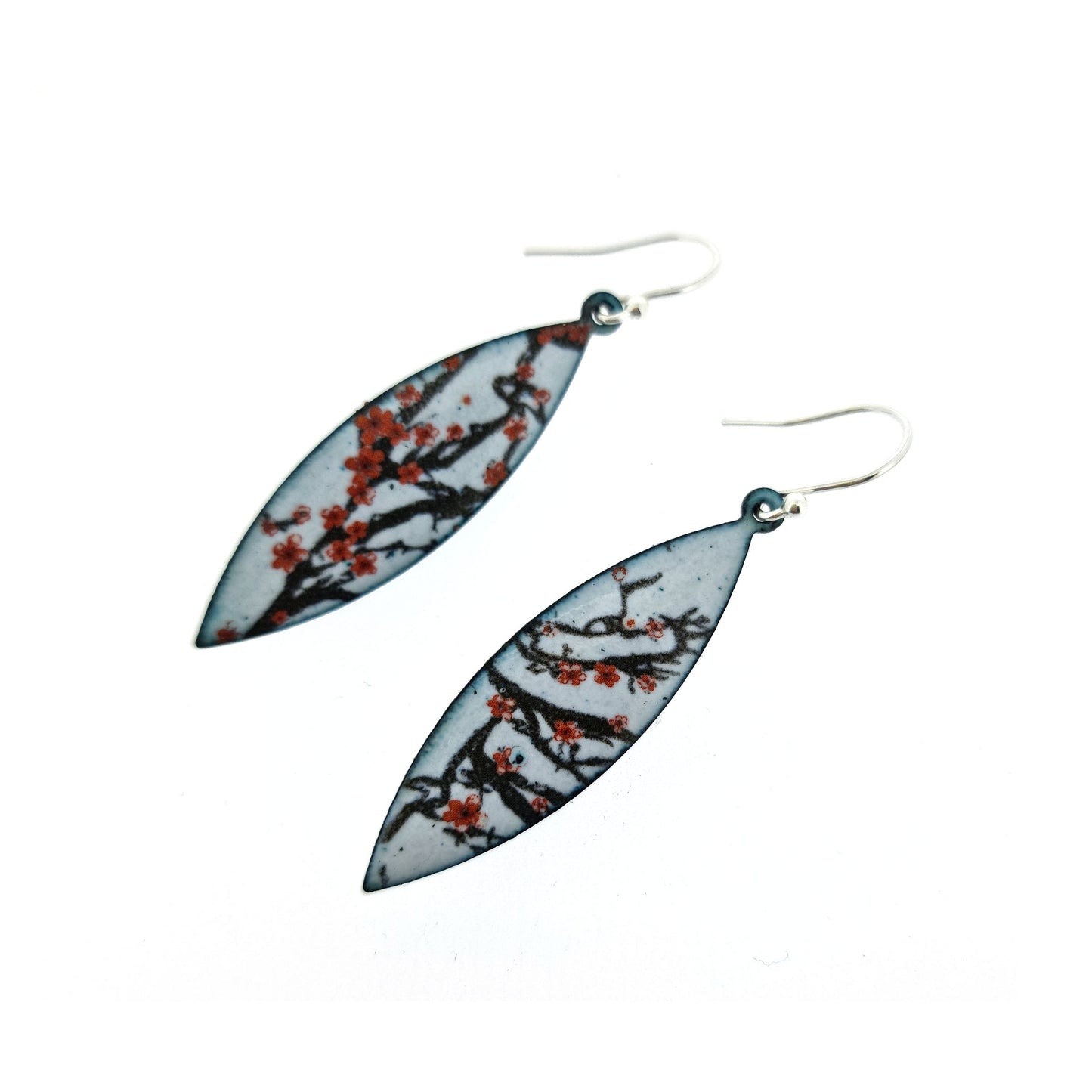 Boat-shaped enamel drop earrings with branches of red cherry blossom on a grey background.