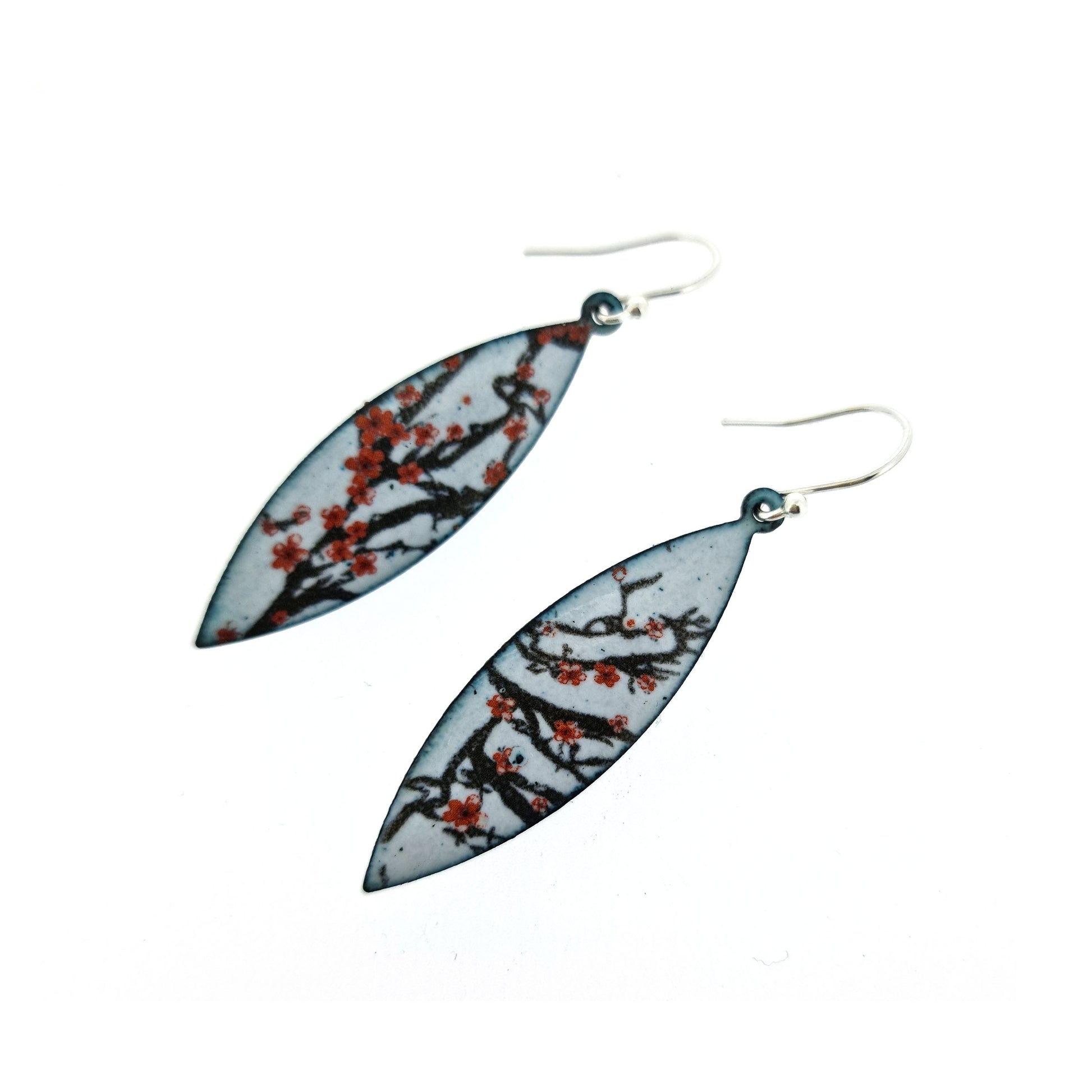 Boat-shaped enamel drop earrings with branches of red cherry blossom on a grey background.