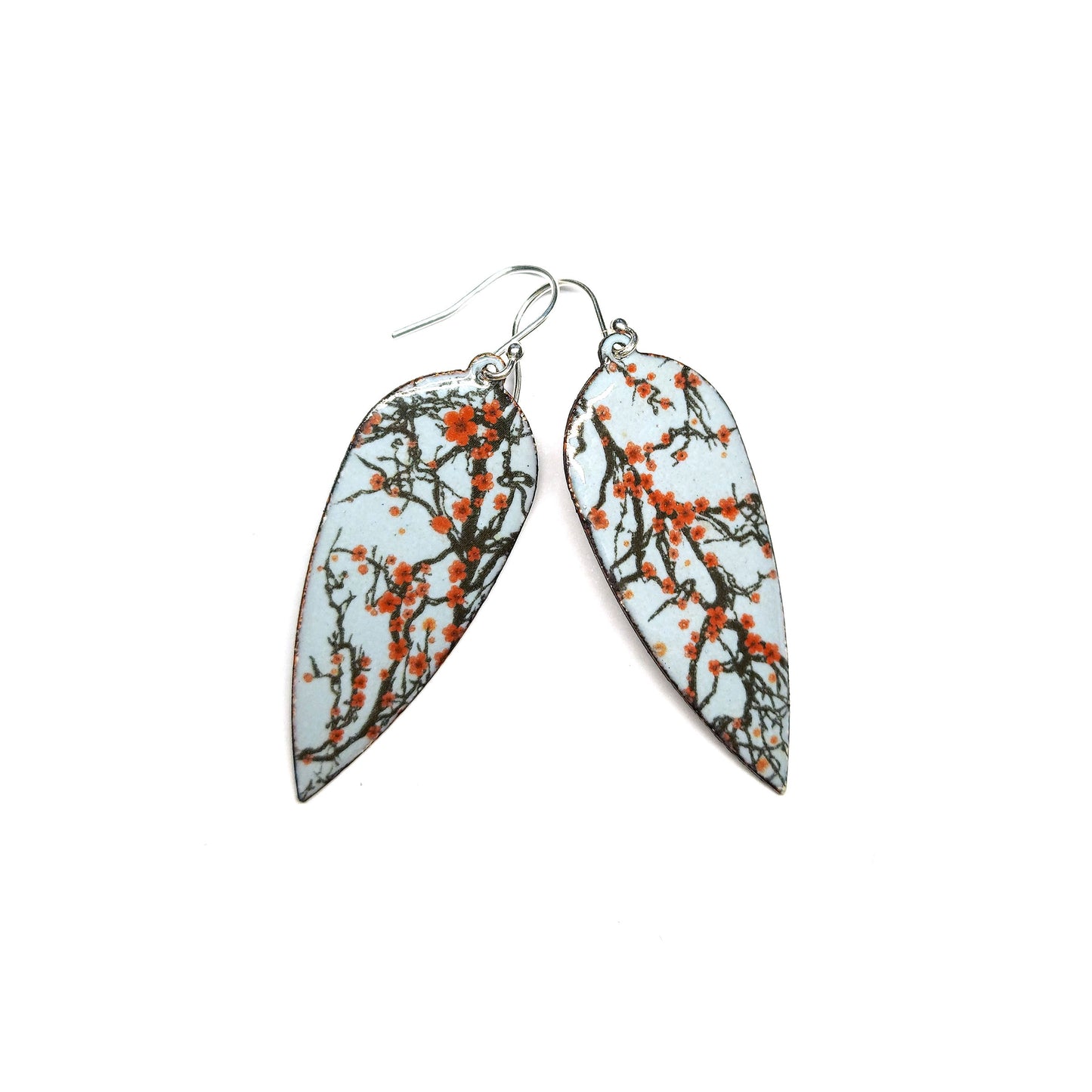 Statement enamel earrings featuring branches and red cherry blossom on a grey enamel background. On silver ear hooks.