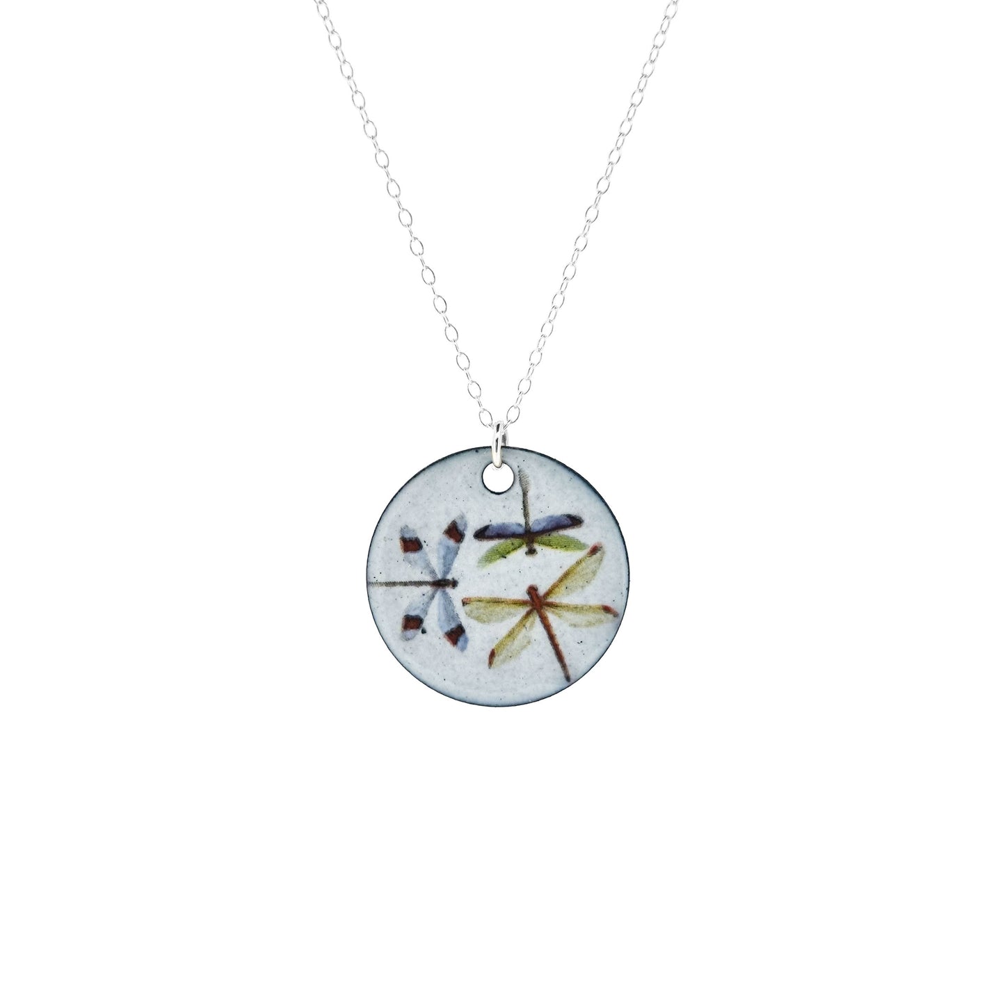 A round enamel pendant hangs from a silver chain. The pendant has a light grey background and 3 dragonflies on it.
