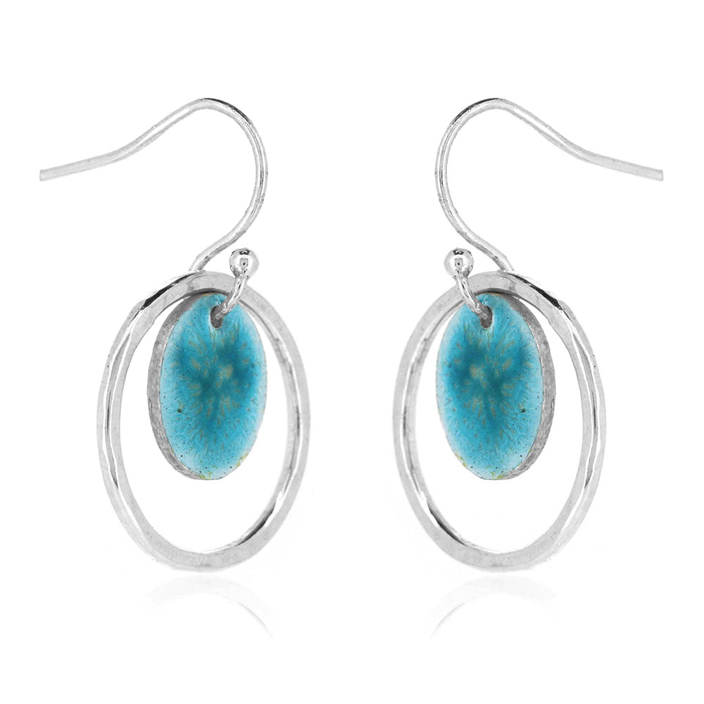 Silver drop earrings with a central silver disc covered with a turquoise enamel pattern and a surrounding hammered silver circle. Side view.