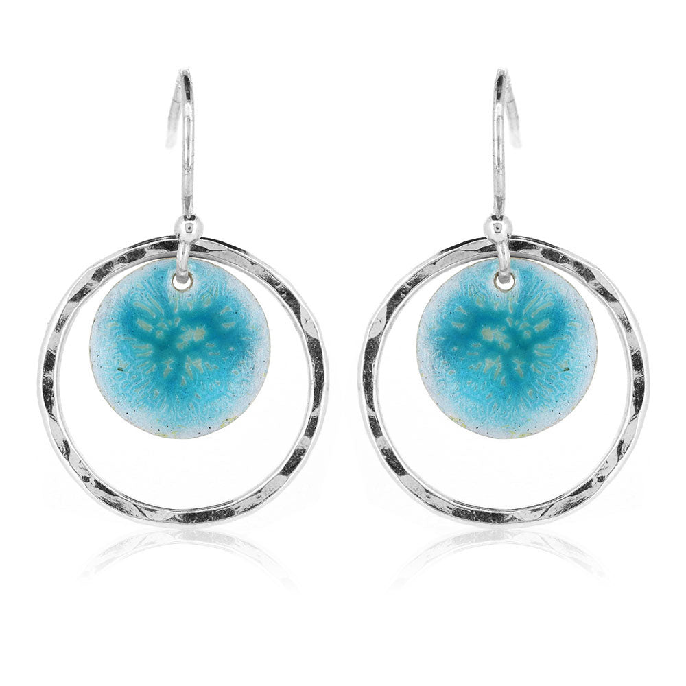 Silver drop earrings with a central silver disc covered with a turquoise enamel pattern and a surrounding hammered silver circle.
