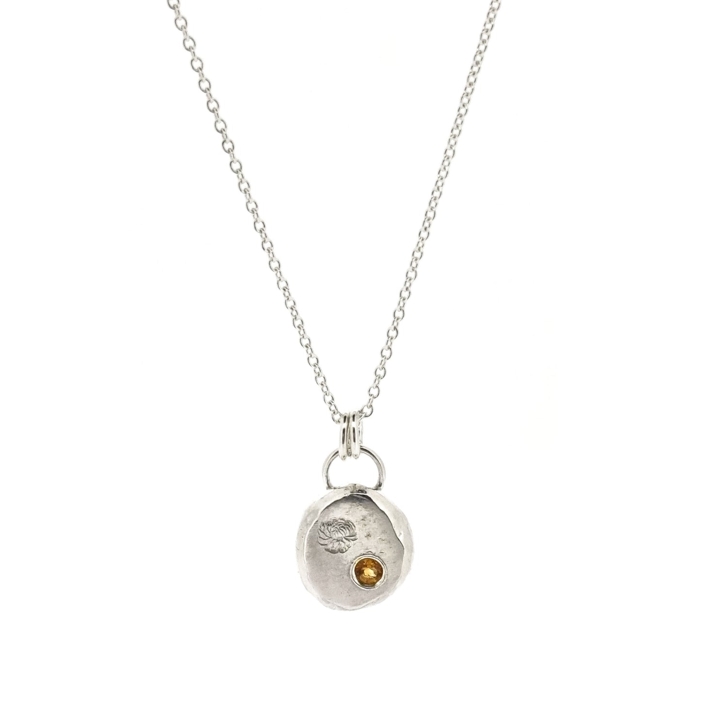 Round silver flat pebble pendant with chrysanthemum flower engraved on it and a flush set yellow citrine gemstone. On a silver chain.