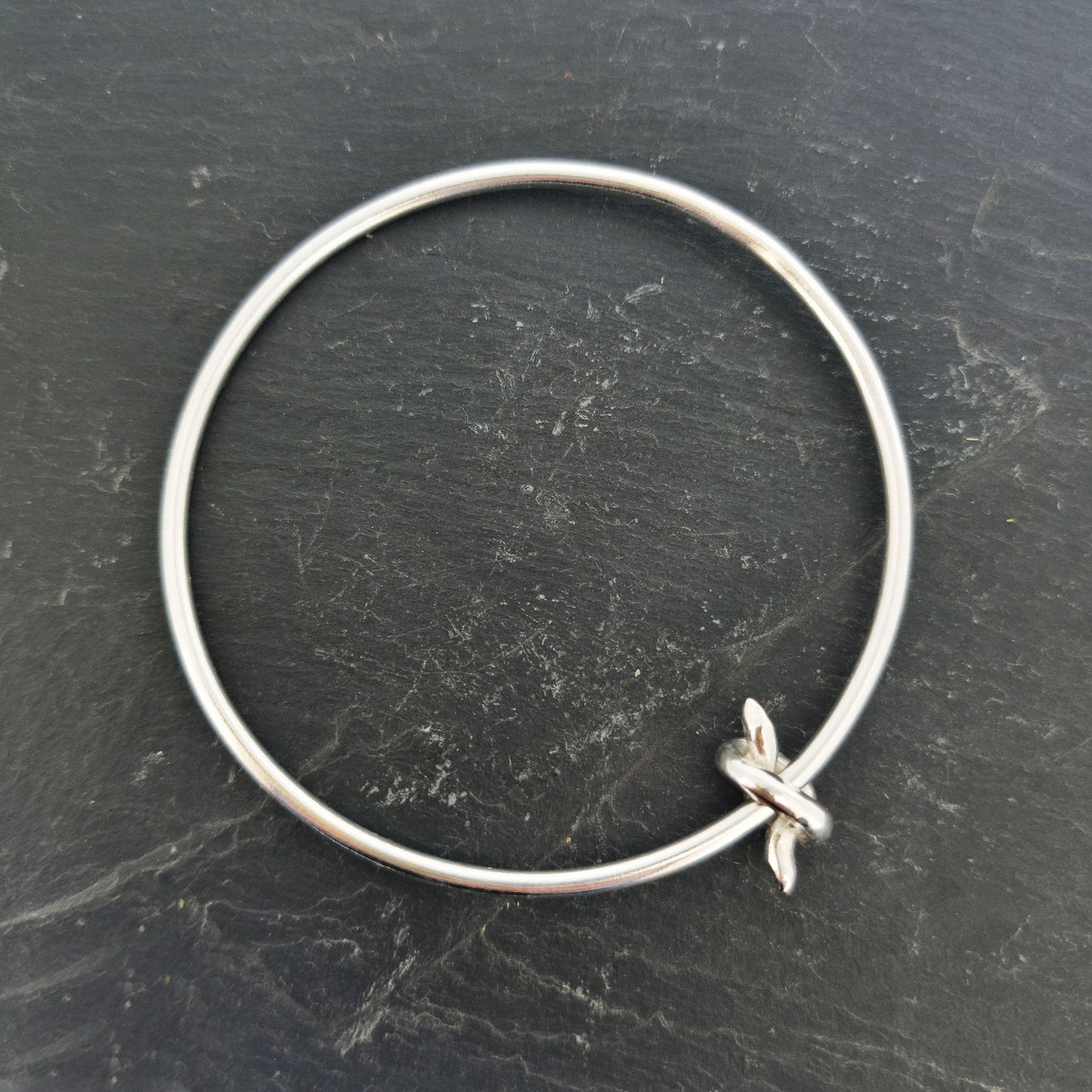 Silver round bangle with spinning knot charm.