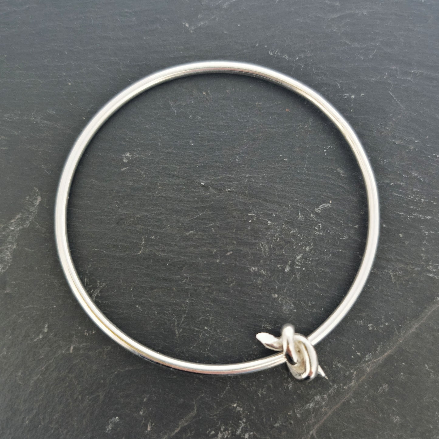 Silver round bangle with spinning knot charm.