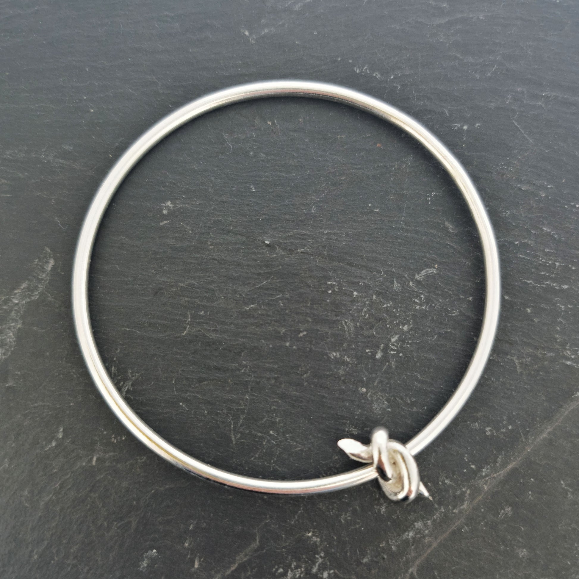 Silver round bangle with spinning knot charm.