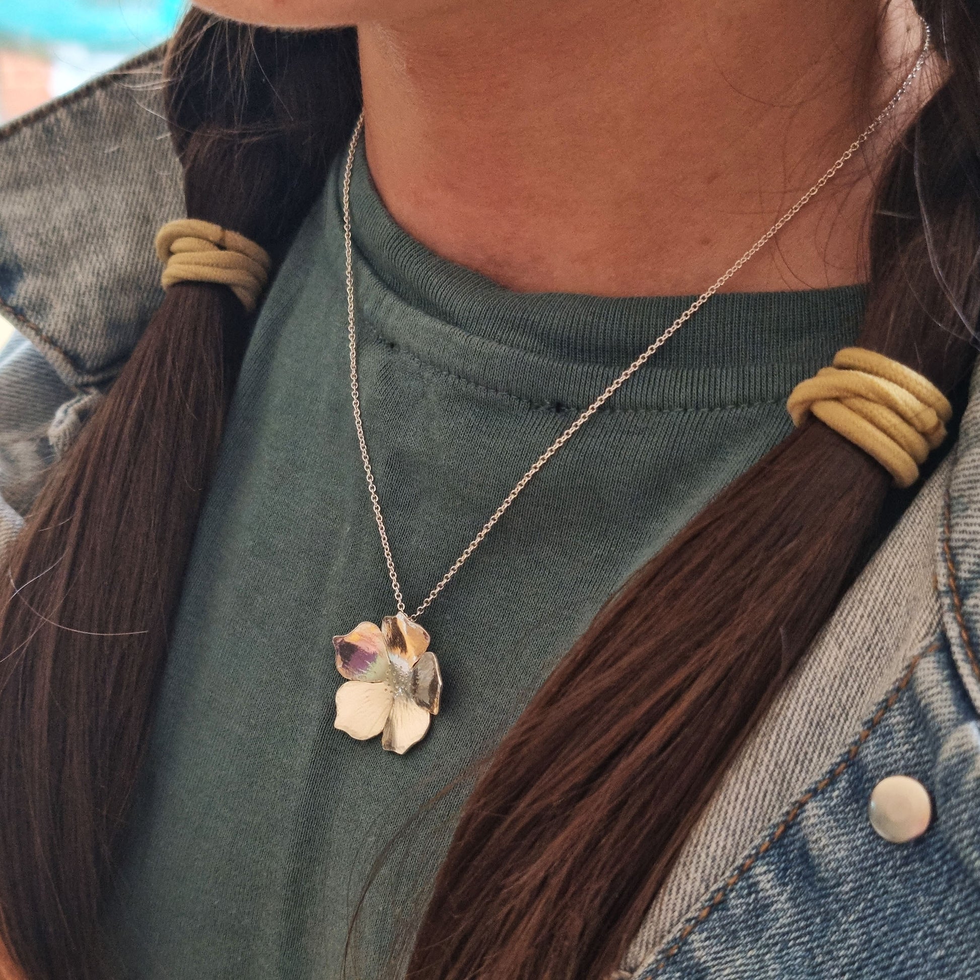 A silver 5 petal flower pendant on silver chain. Pictured being worn.
