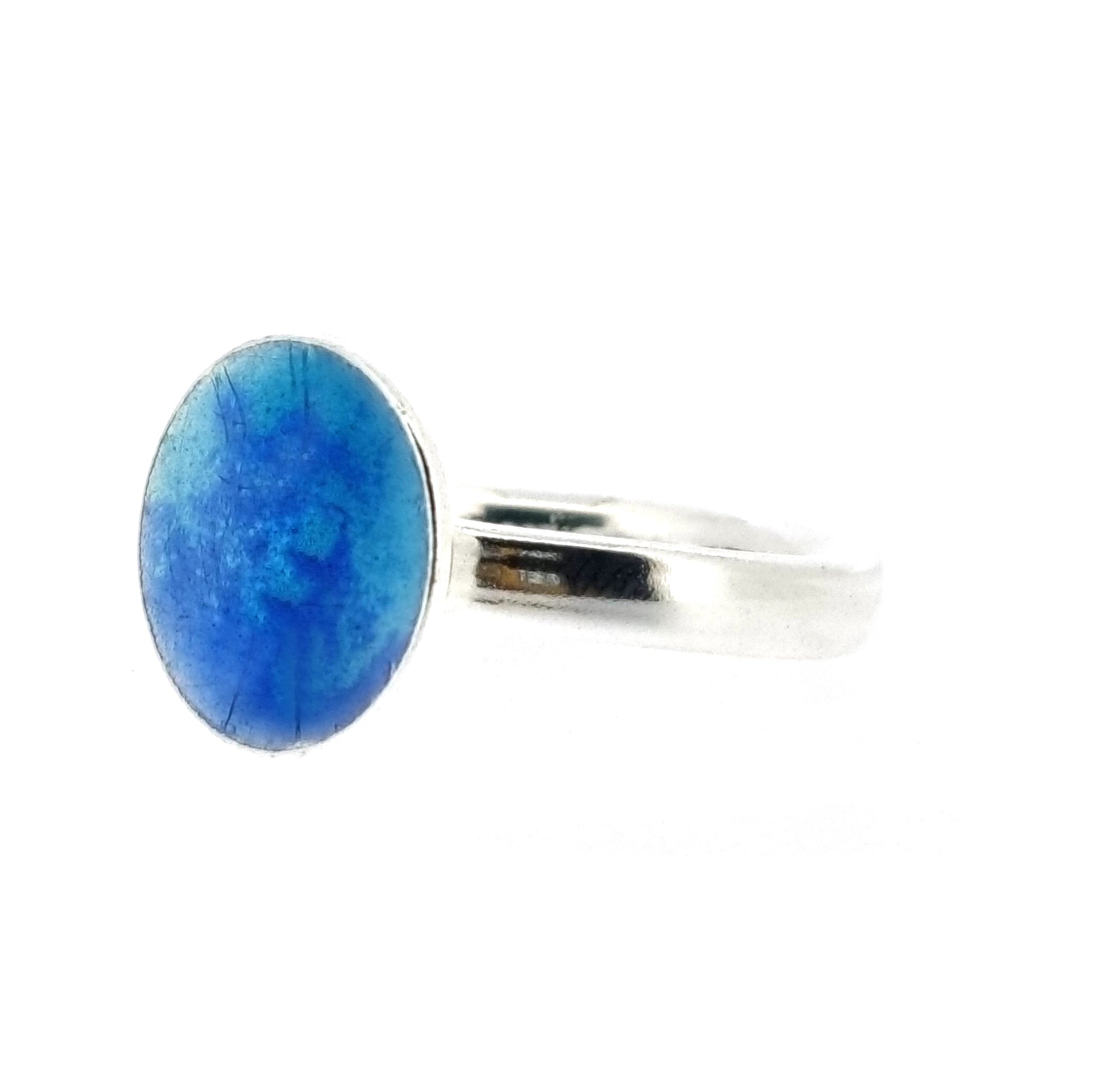 A silver ring band with a round silver top coloured with dark blue and turquoise blue enamel.