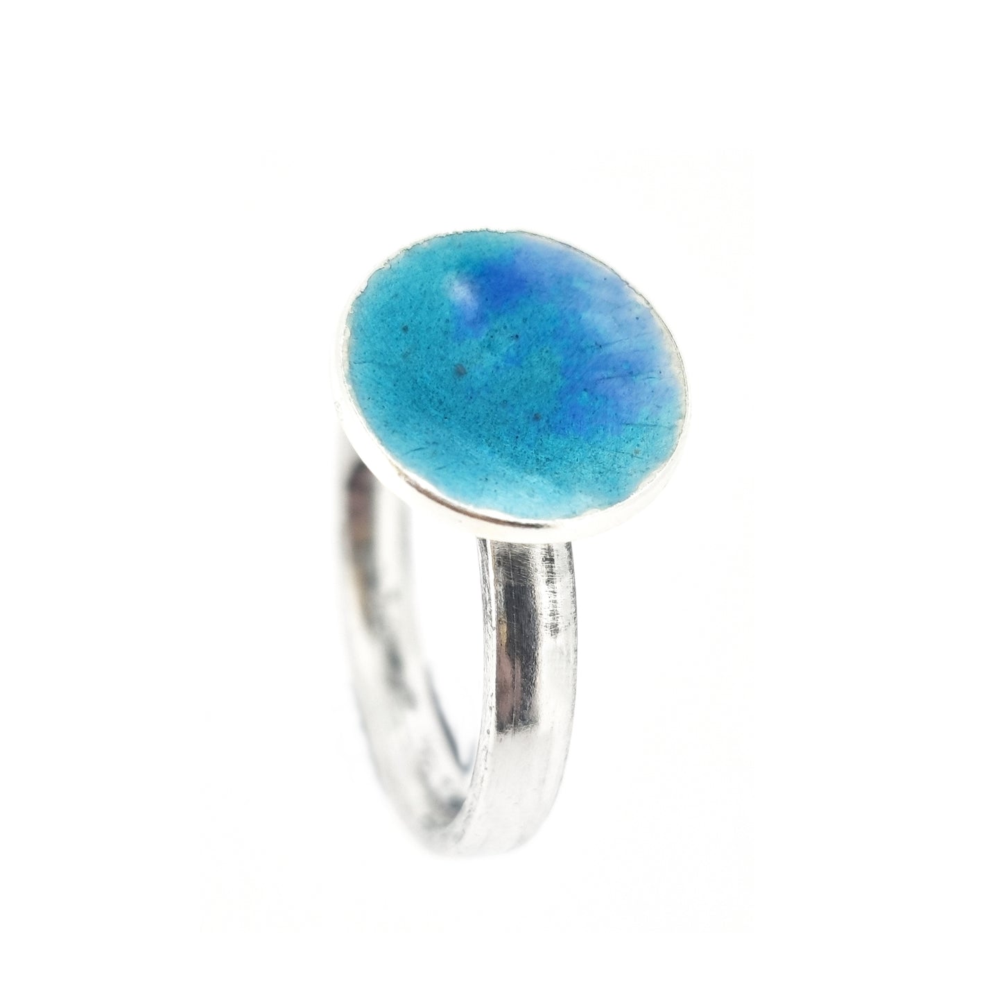 A silver ring band with a round silver top coloured with turquoise and turquoise blue enamel.