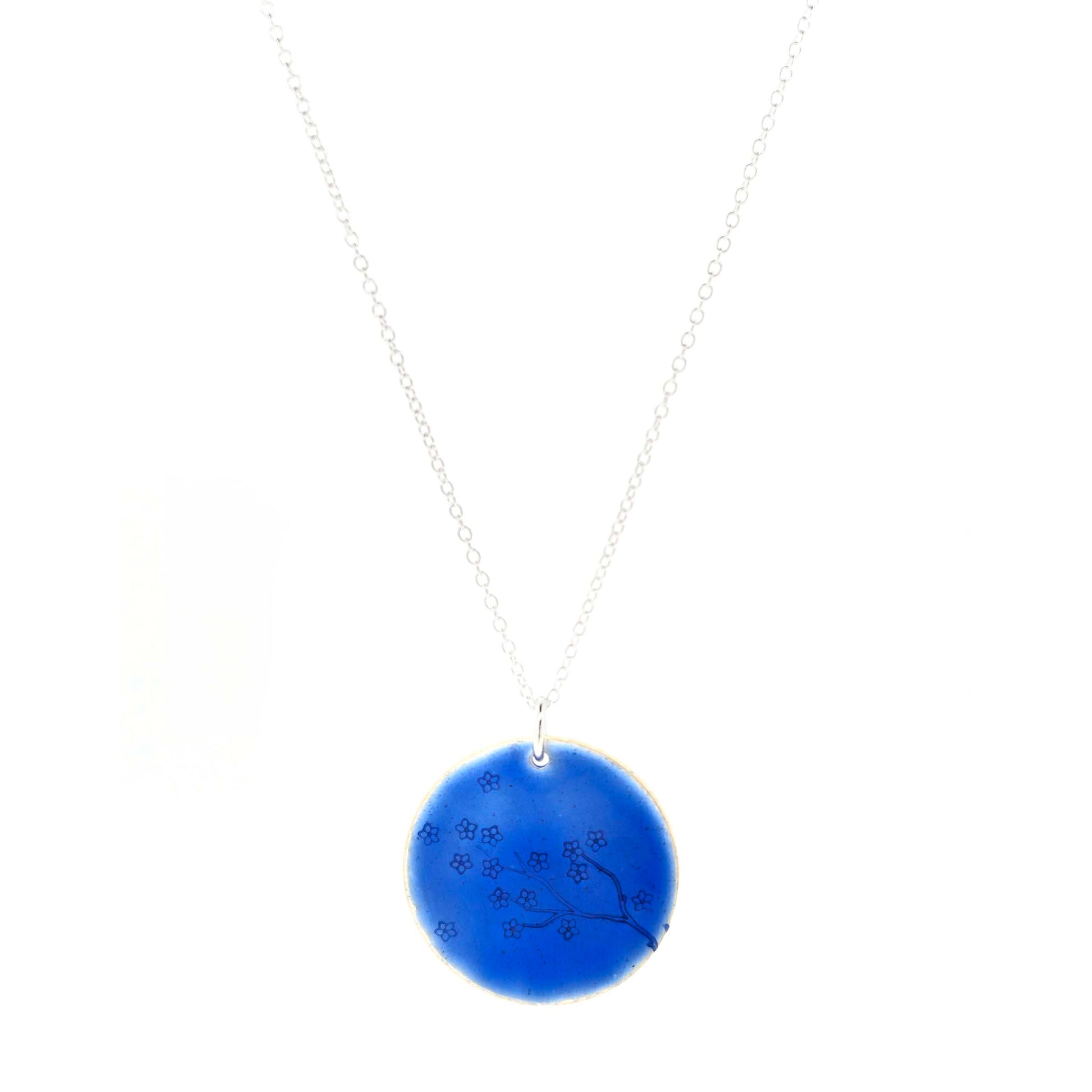 Silver and blue enamel pendant necklace with a flower branch design on a white background.