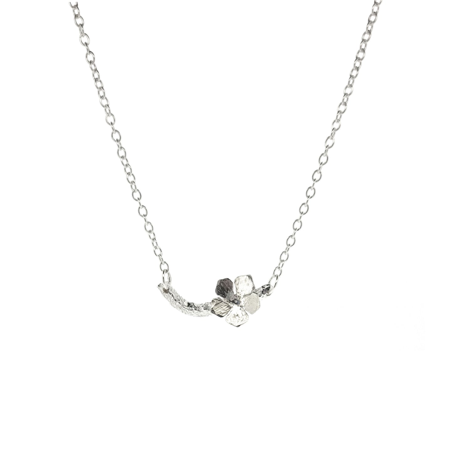 Silver necklace with small branch and a single 5 petal flower on it.