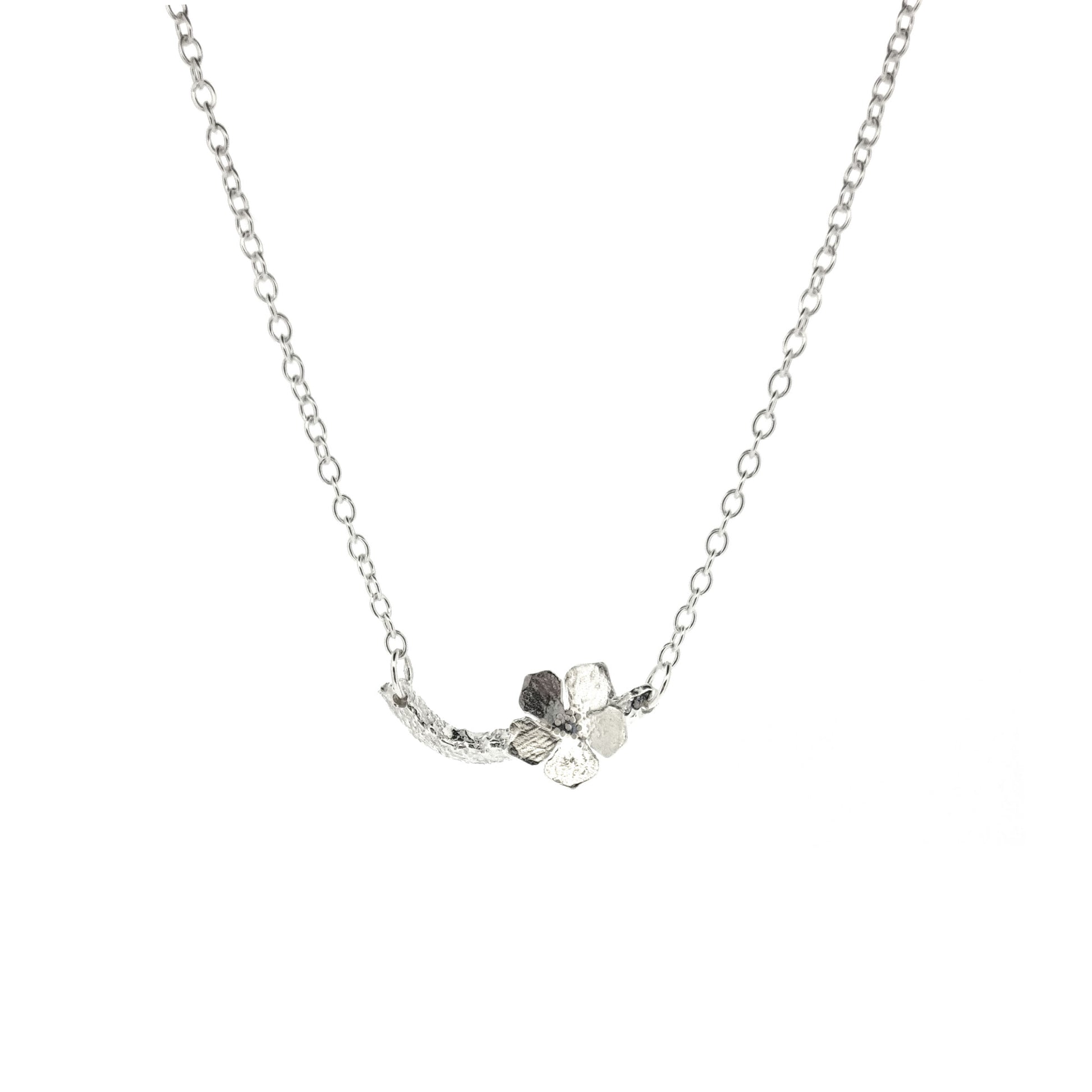 Silver necklace with small branch and a single 5 petal flower on it.