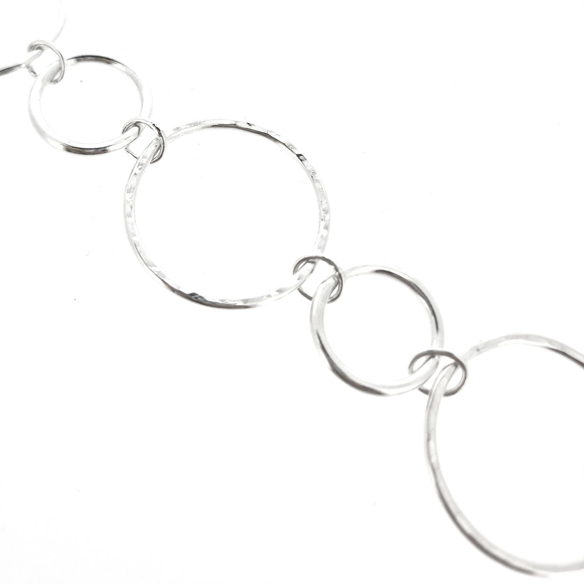 Silver chain link bracelet with 2 sizes of circles, one size has a hammered finish