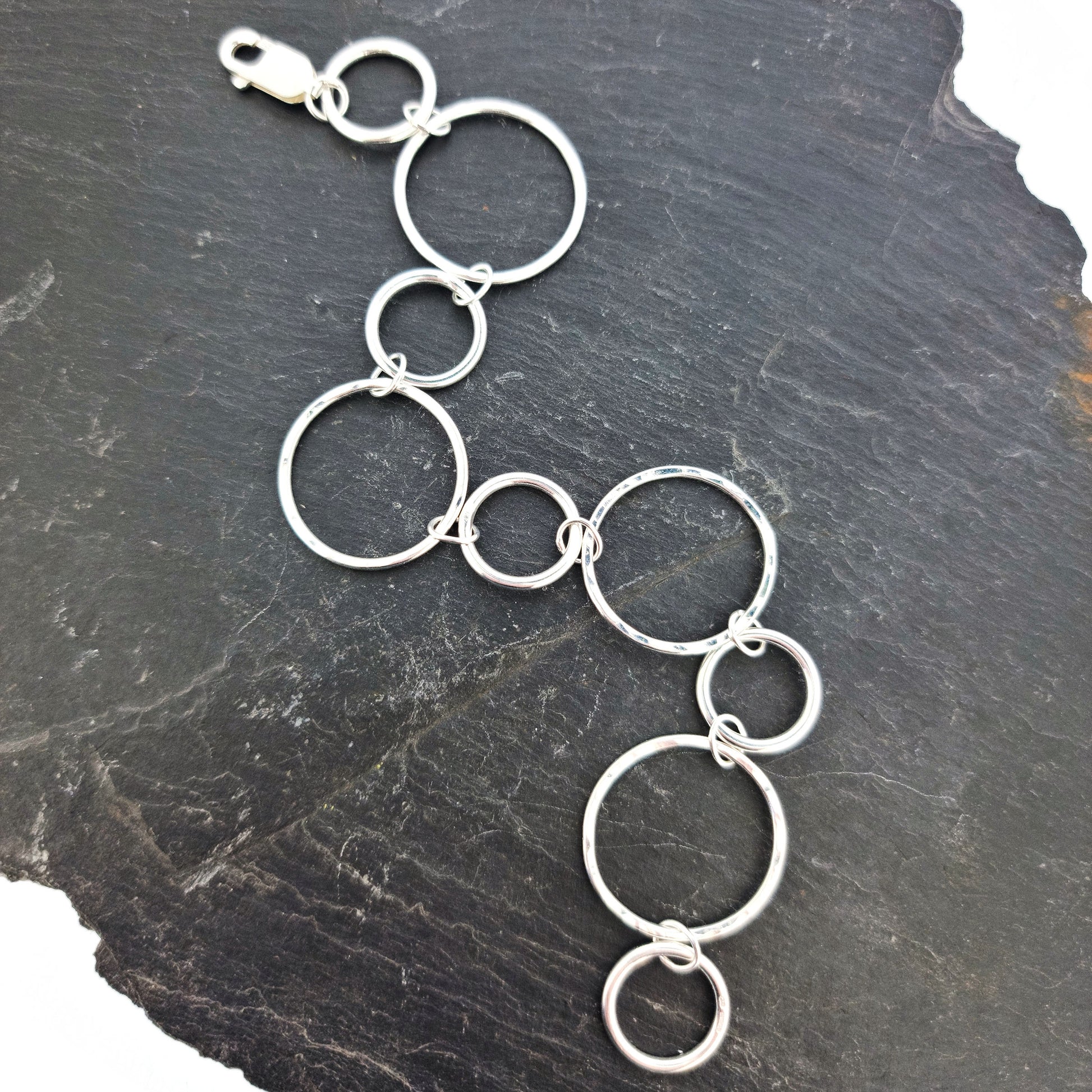 Silver chain link bracelet with 2 sizes of circles, one size has a hammered finish
