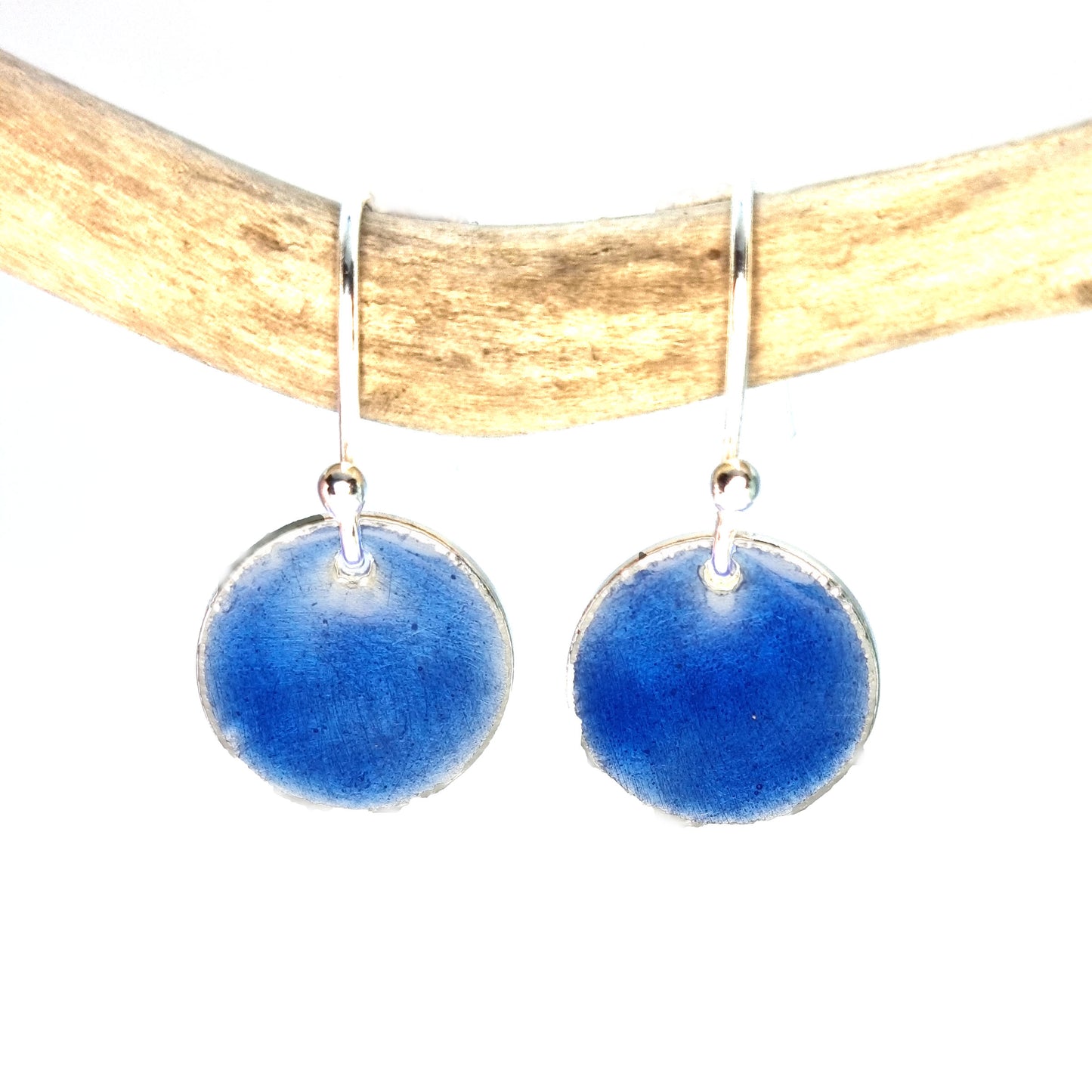 Round silver drop earrings with dark blue enamel. Suspended from twig.