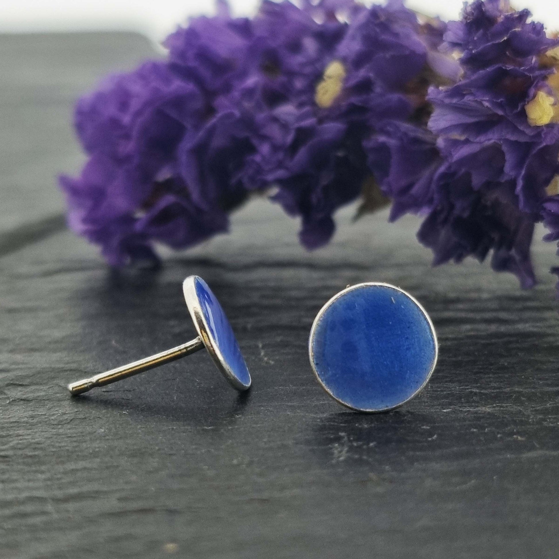 Round silver stud earrings with royal blue enamel. Pictured with flowers.