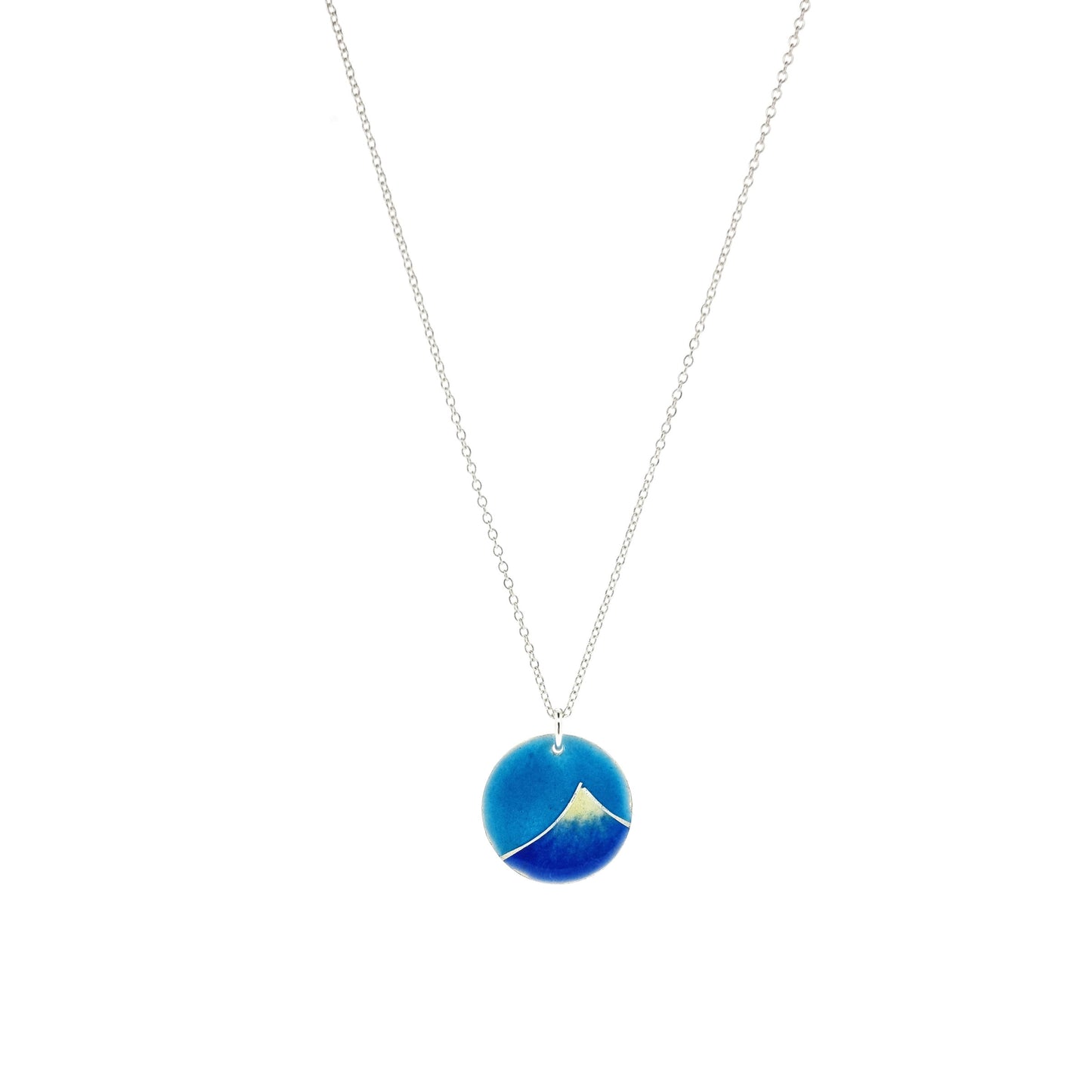 Silver and enamel round pendant featuring a dark blue and white mountain with a turquoise blue sky. On a silver chain.