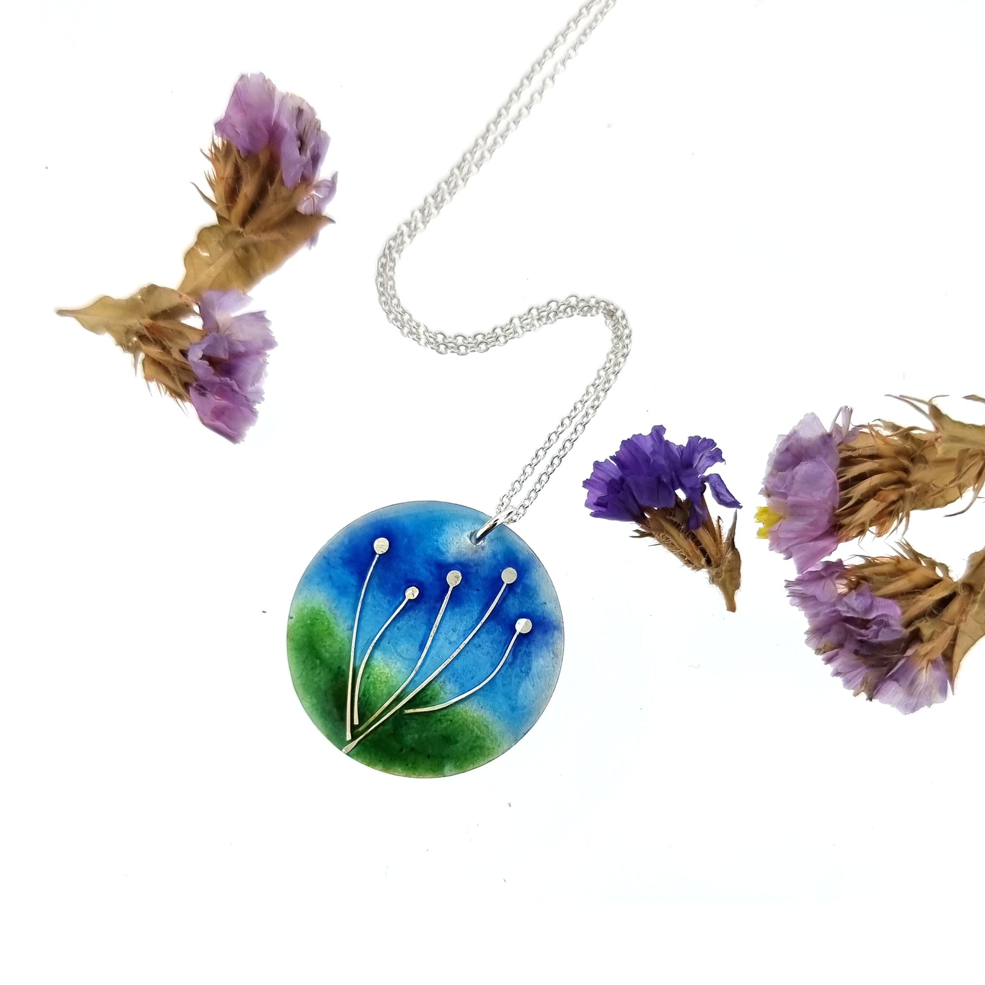 Round silver pendant with silver flowers and blue & green enamels. On silver chain. With flowers