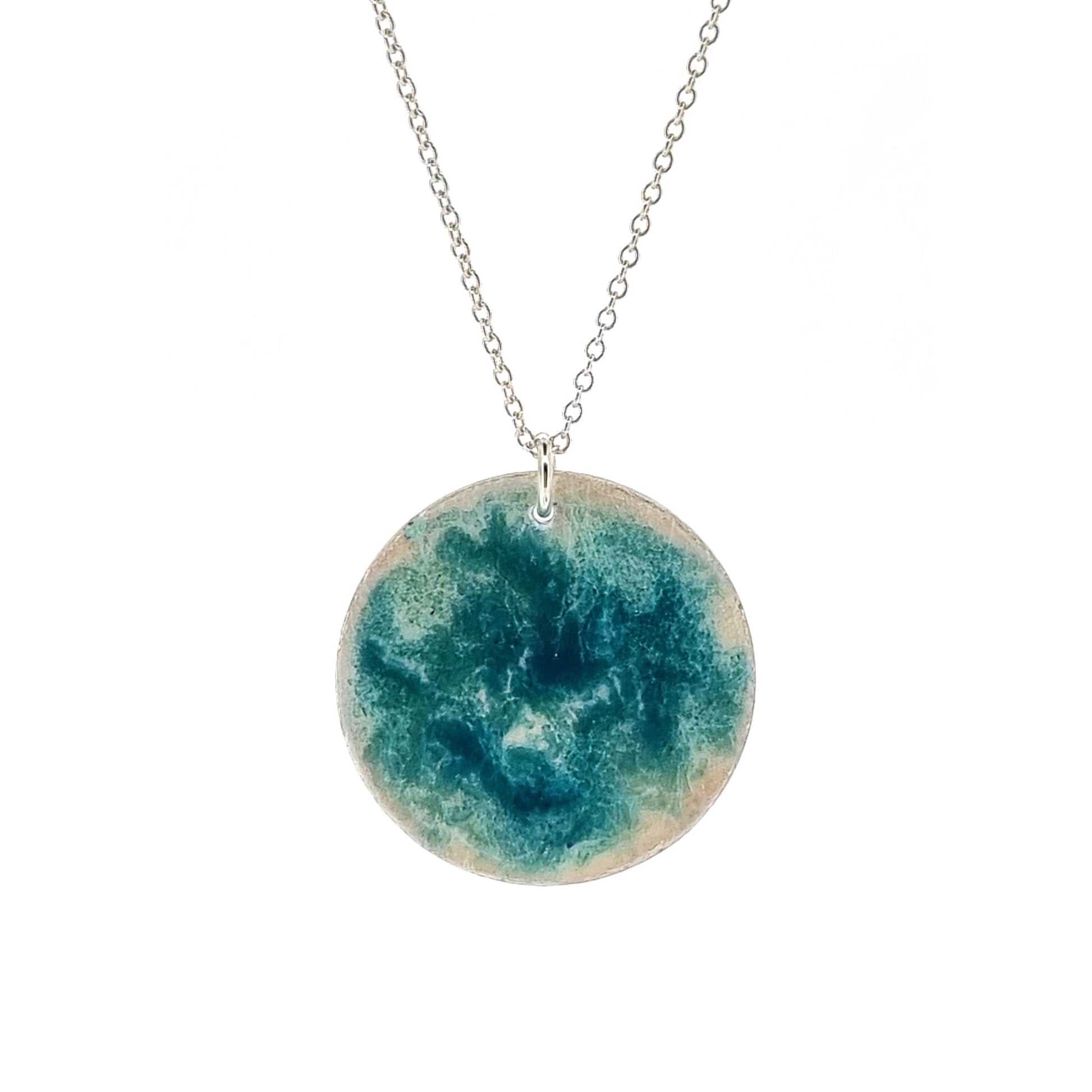 Round silver pendant with turquoise swirl enamel pattern. On silver chain.