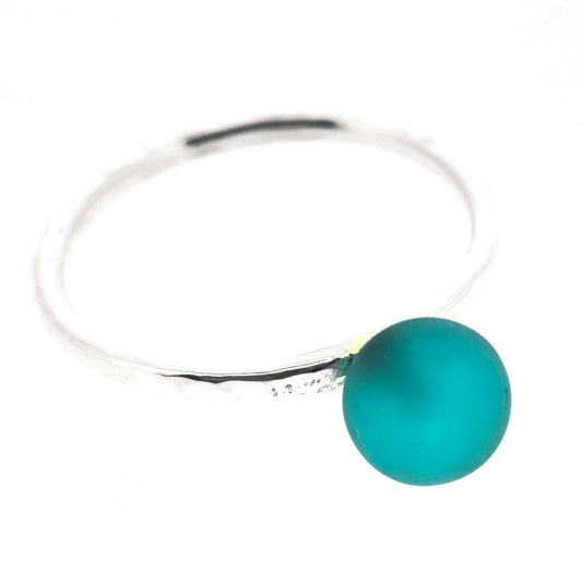 A ring made up of a thin silver band with a hammered finish and a turquoise glass sphere on top. Mijoux Creations.