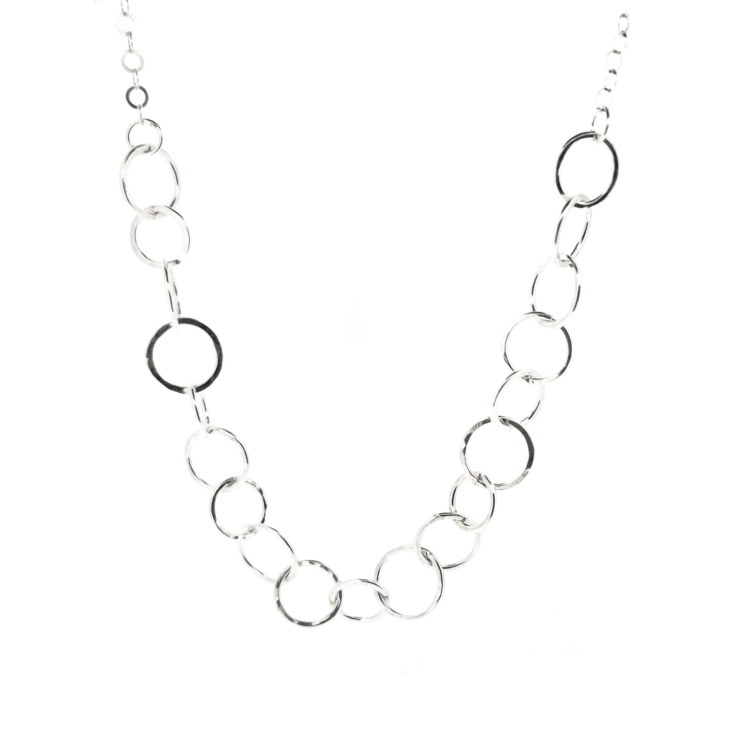 A silver necklace made up of different size circles with a hammered finish and smaller silver chain at the back.
