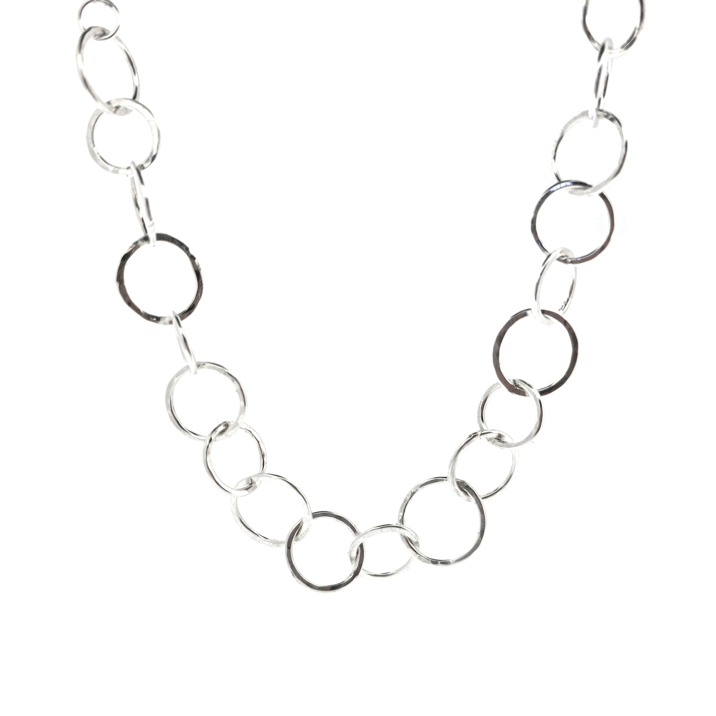 A silver necklace made up of different size circles with a hammered finish