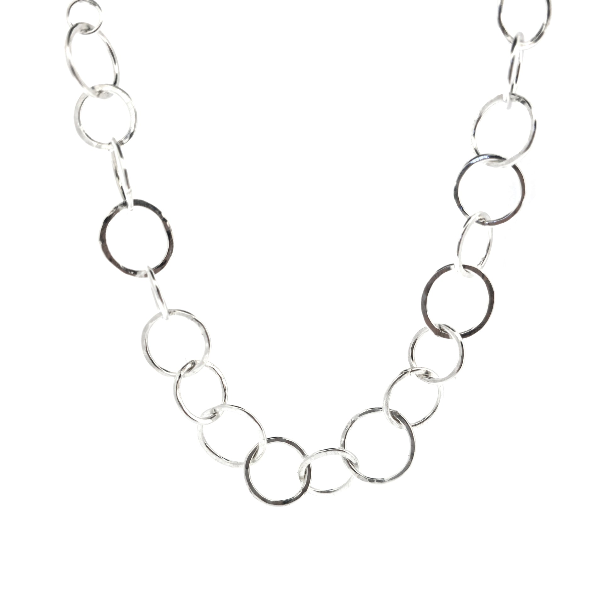 A silver necklace made up of different size circles with a hammered finish