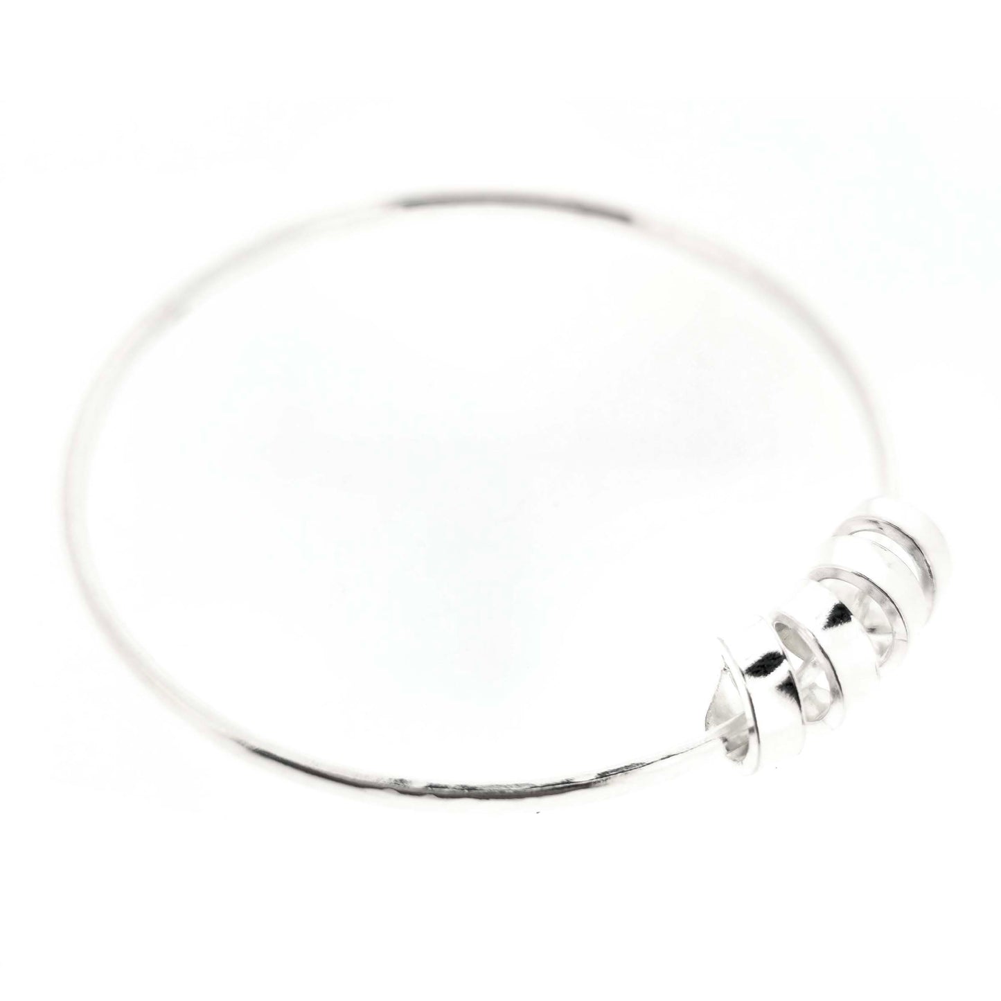 Silver bangle with a hammered finish and a wide spiral bead on a white background.