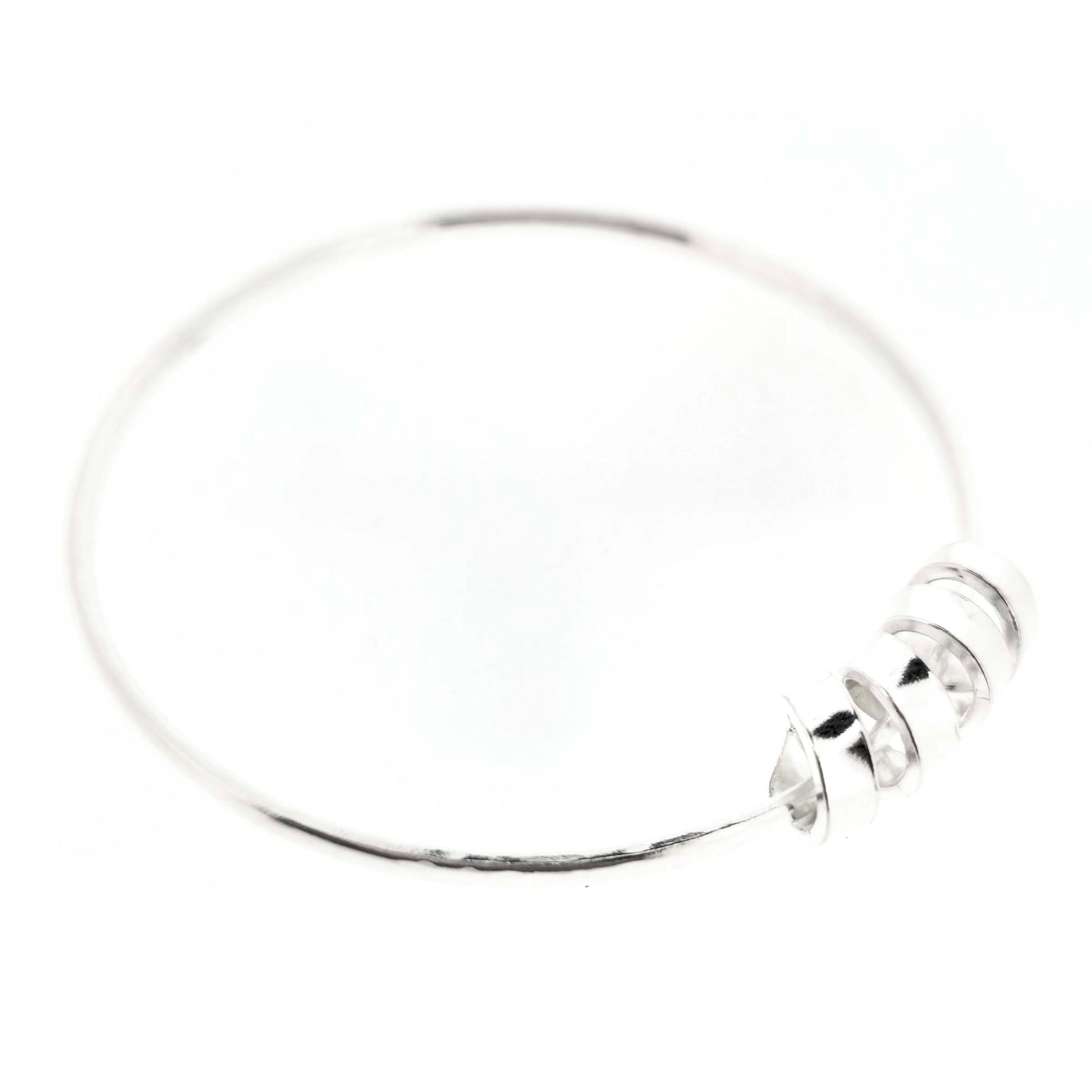 Silver bangle with a hammered finish and a wide spiral bead on a white background.