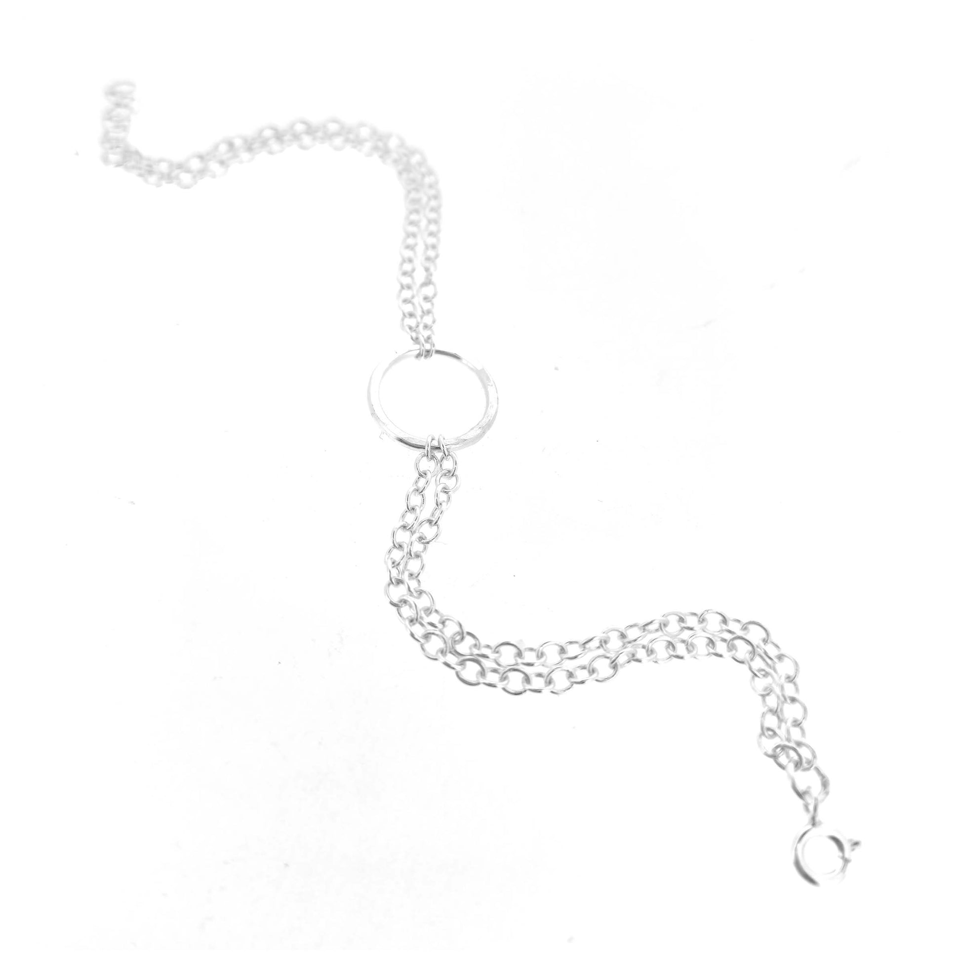 Silver double chain bracelet with a central hammered circle on a white background