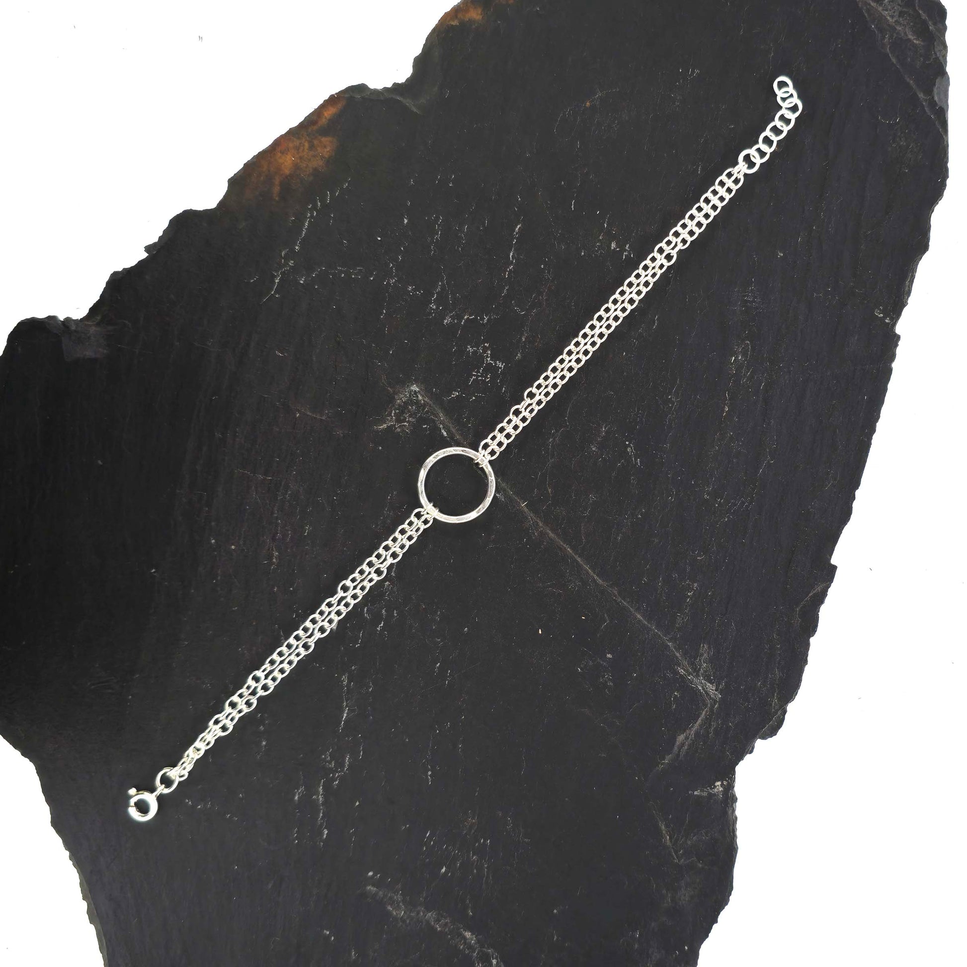 Silver double chain bracelet with a central hammered circle on a slate background