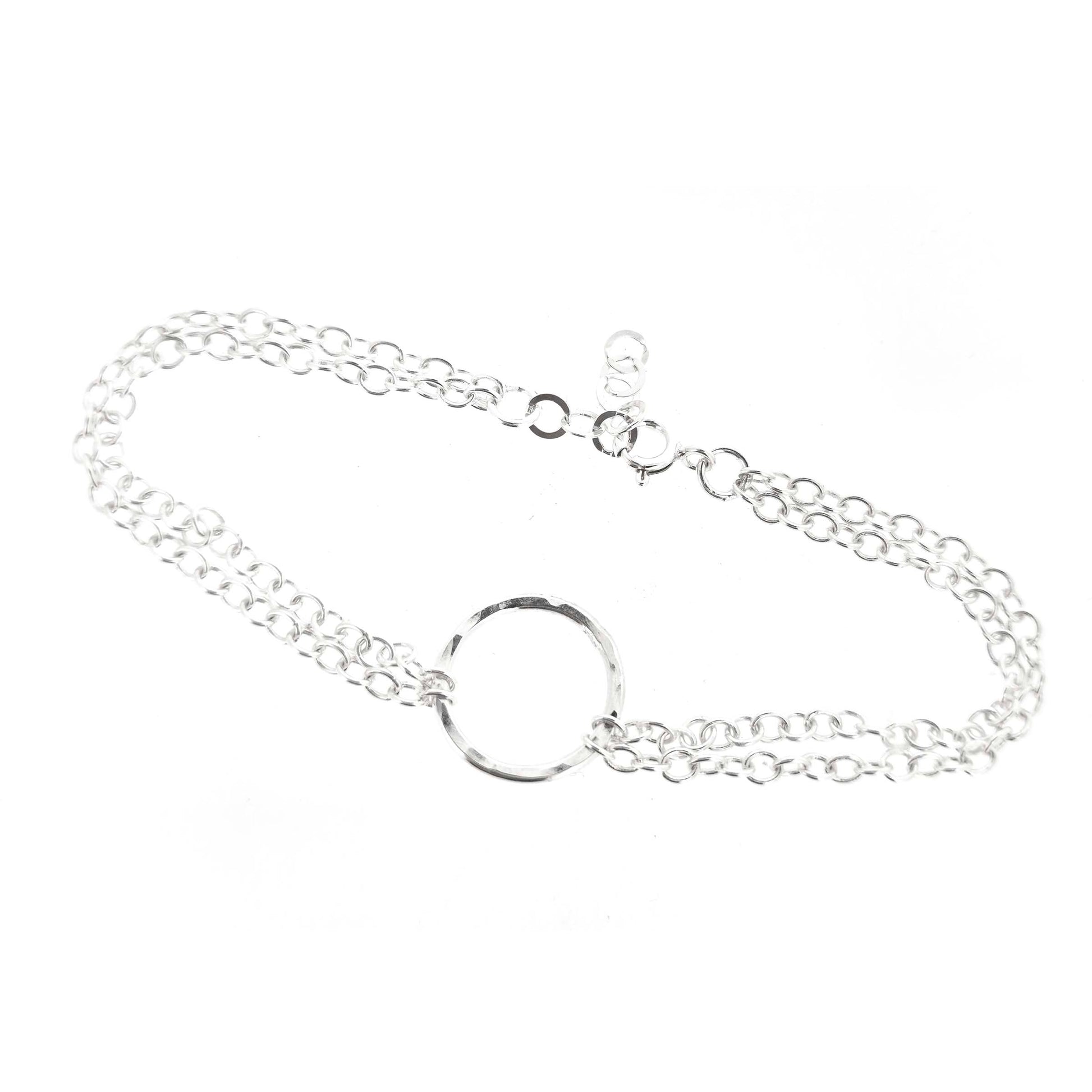 Silver double chain bracelet with a central hammered circle on a white background