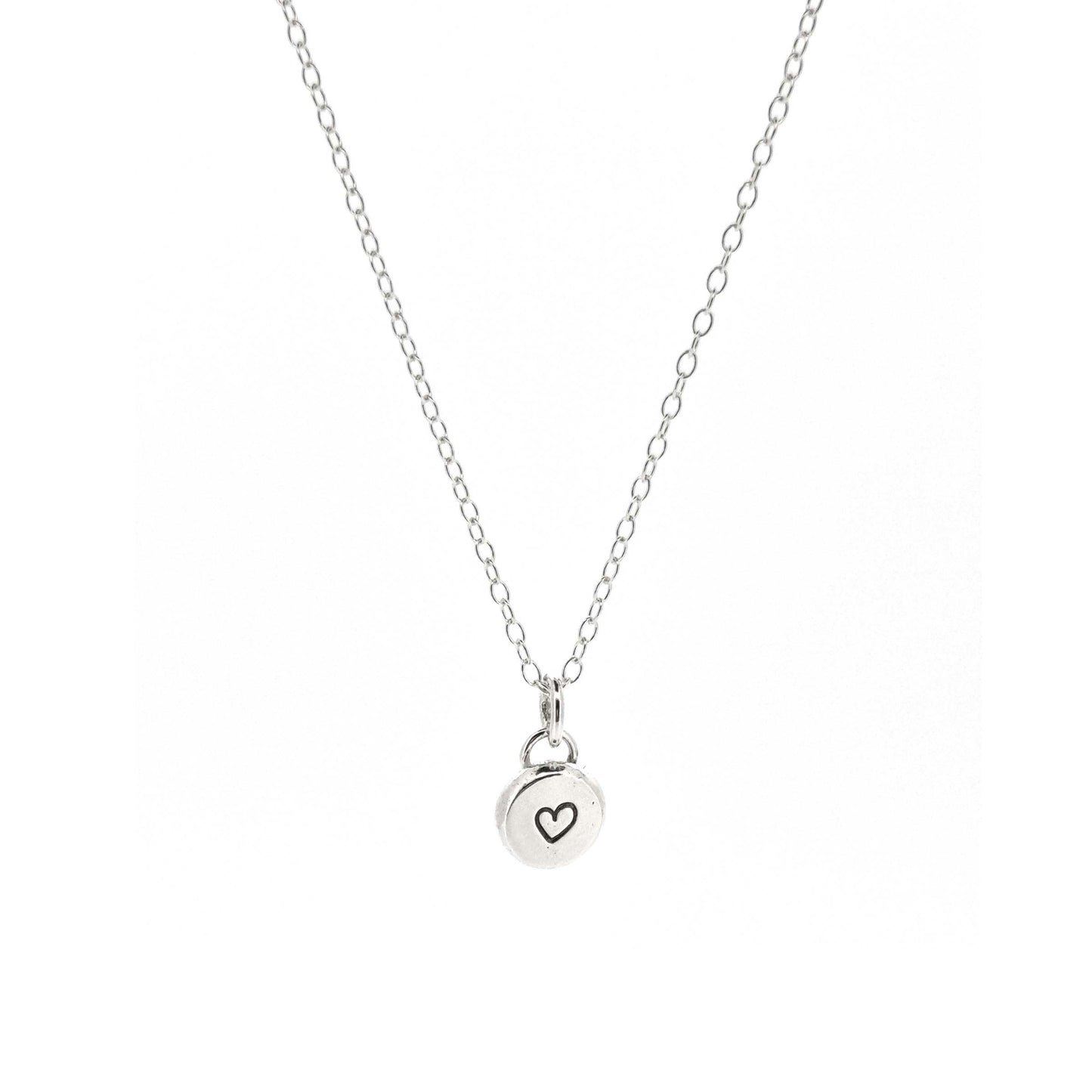 A round silver flat pebble pendant with a black heart in the centre. On a silver chain. Small.