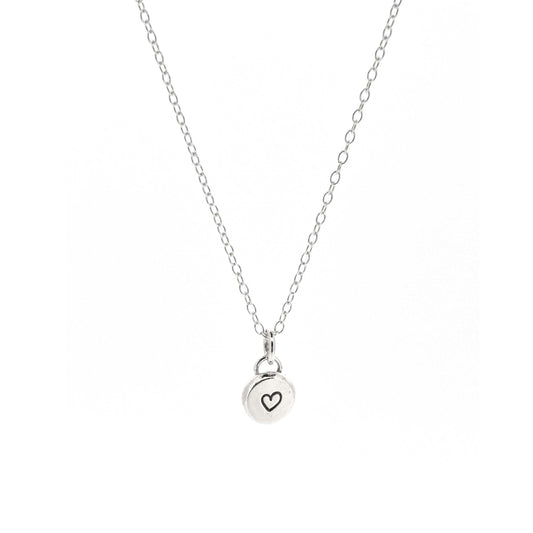 A round silver flat pebble pendant with a black heart in the centre. On a silver chain. Small.