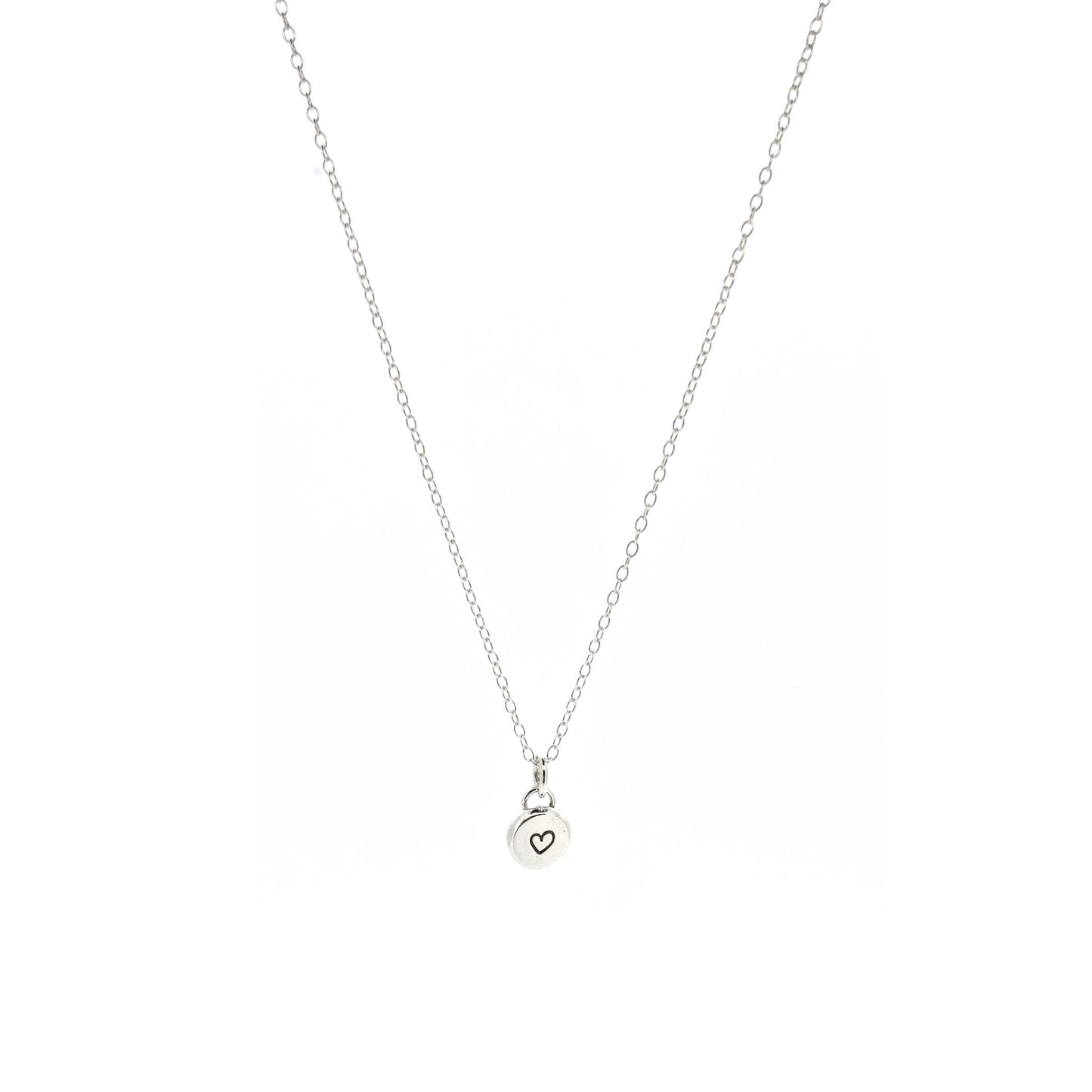 A round silver flat pebble pendant with a black heart in the centre. On a silver chain. Small.