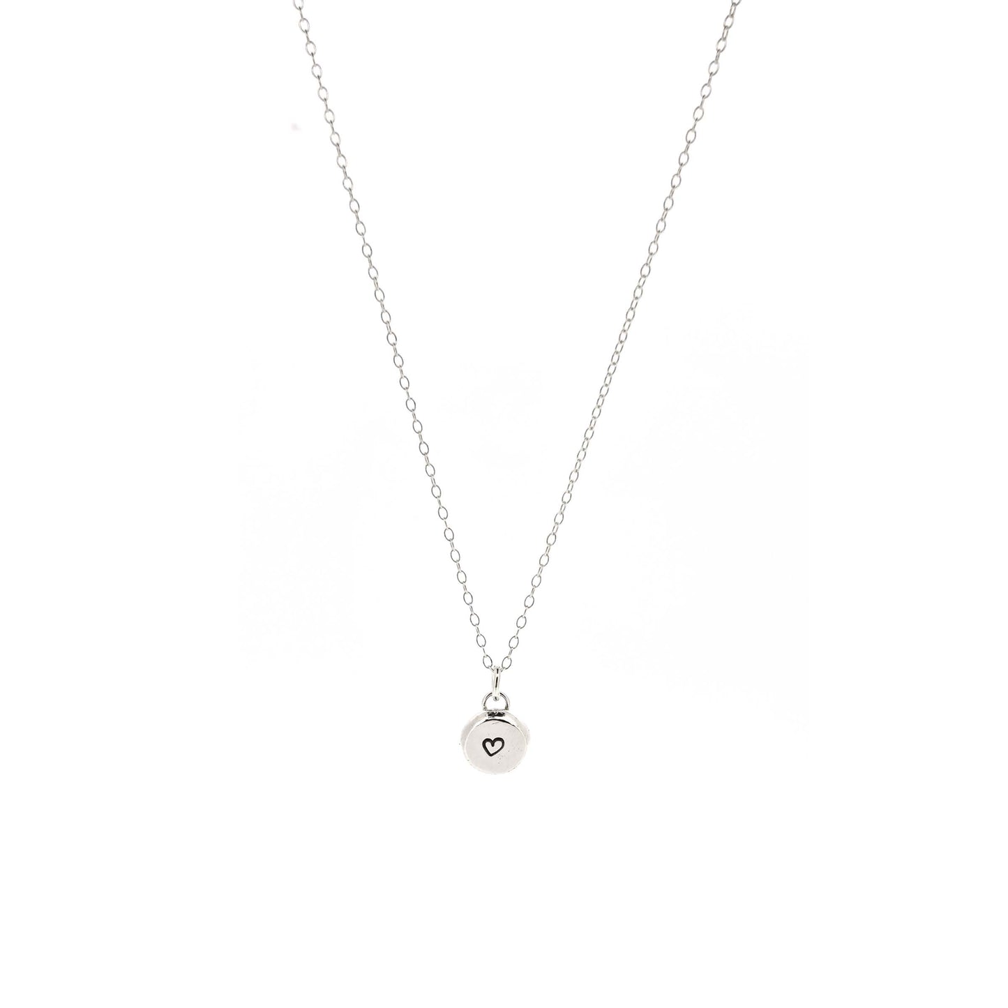 A round silver flat pebble pendant with a black heart in the centre. On a silver chain. Medium.