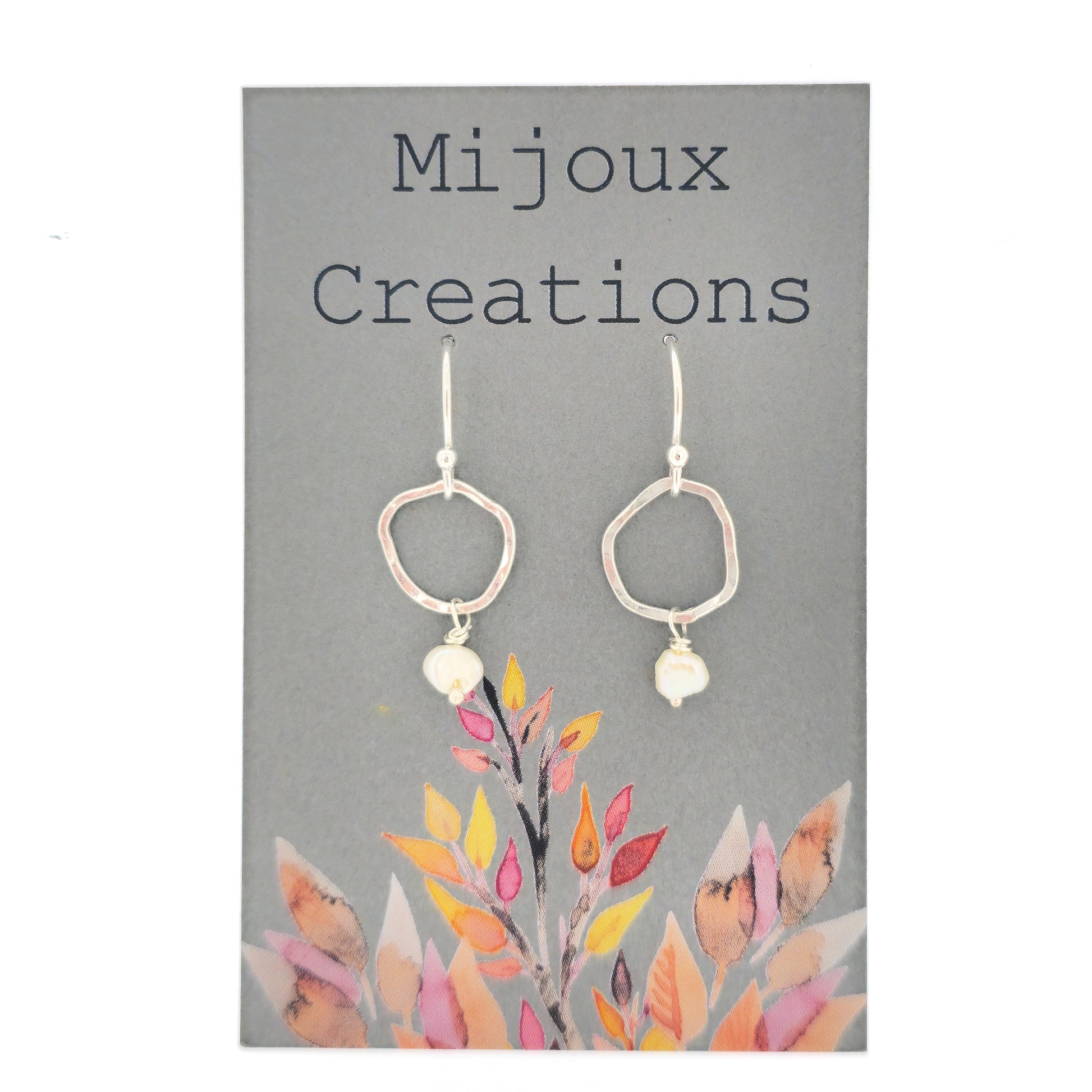 Silver drop earrings consisting of an organic rustic style open circle with a hammered finish suspended from silver ear hooks and with a white pearl hanging from it. Small.