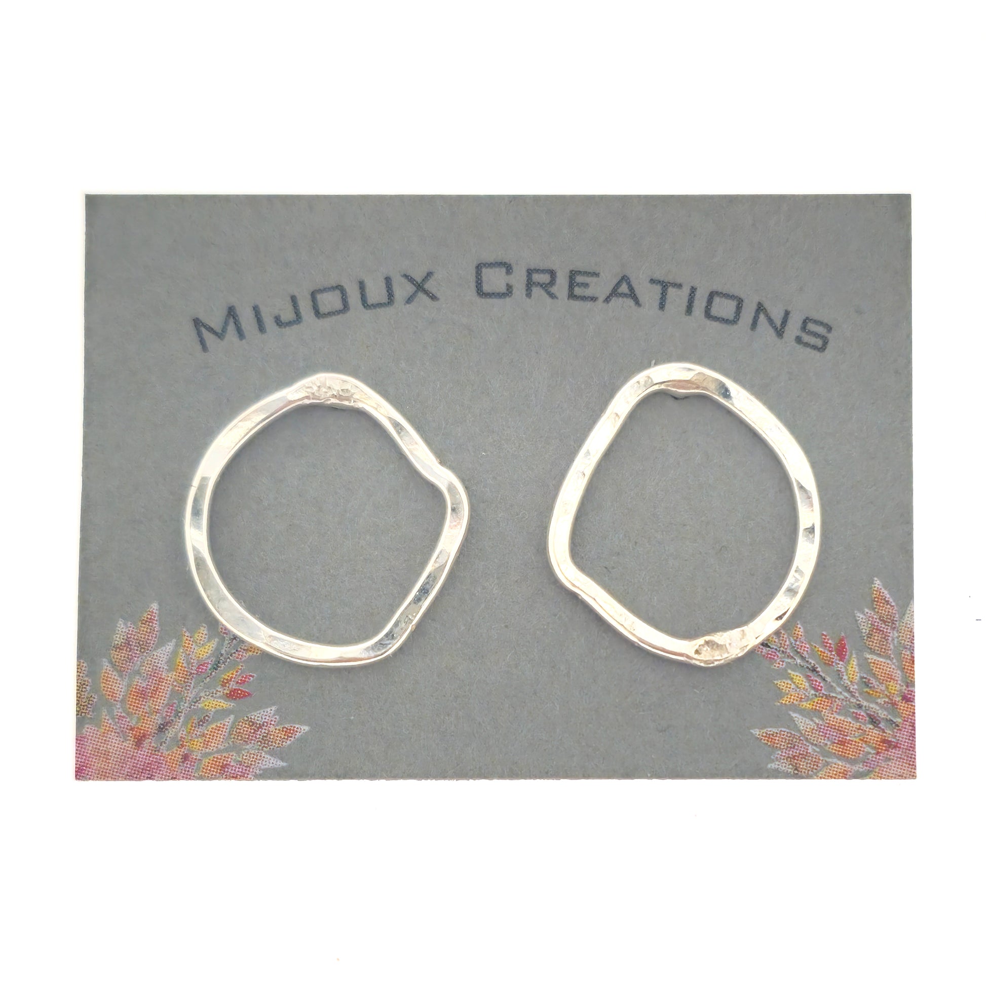 Silver open stud earrings of an organic rustic circle shape - small. Shown on a Mijoux card.