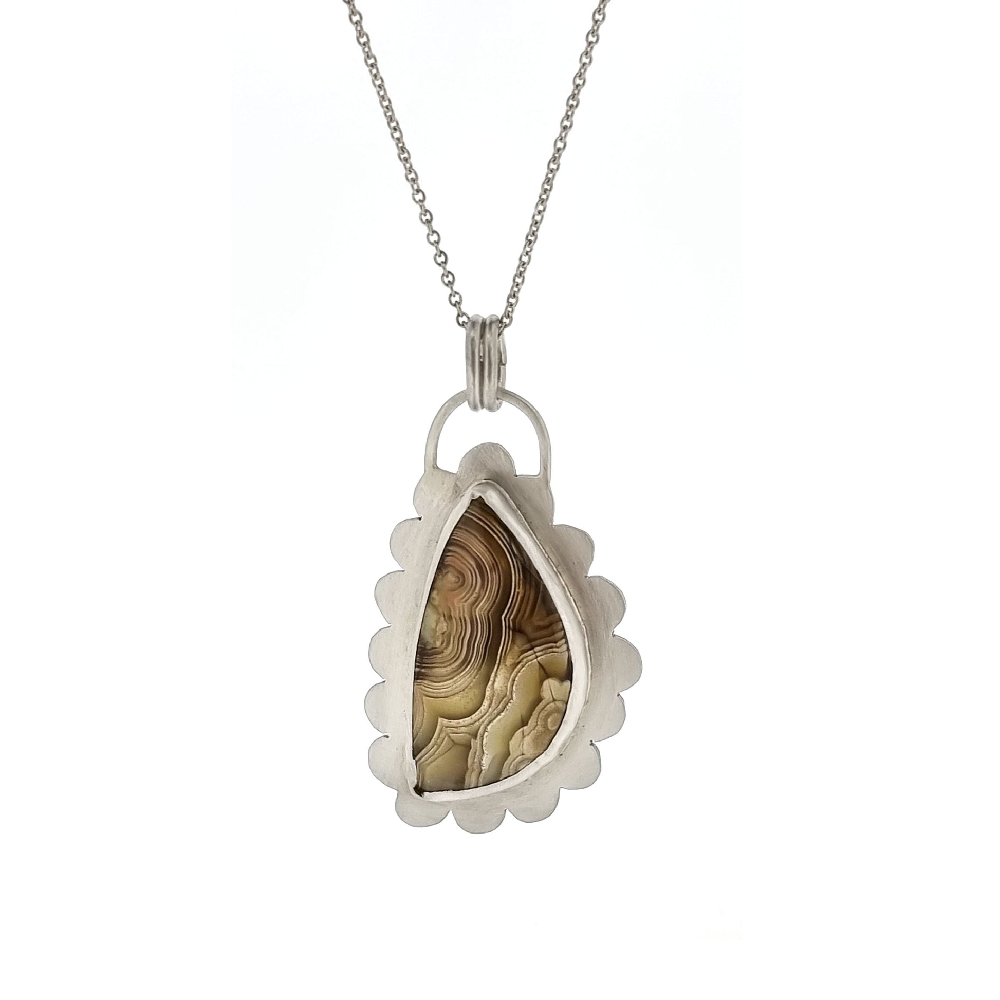 Silver pendant with brown jasper gemstone with curbed striations in a silver surround shaped like a cloud. On a silver chain.