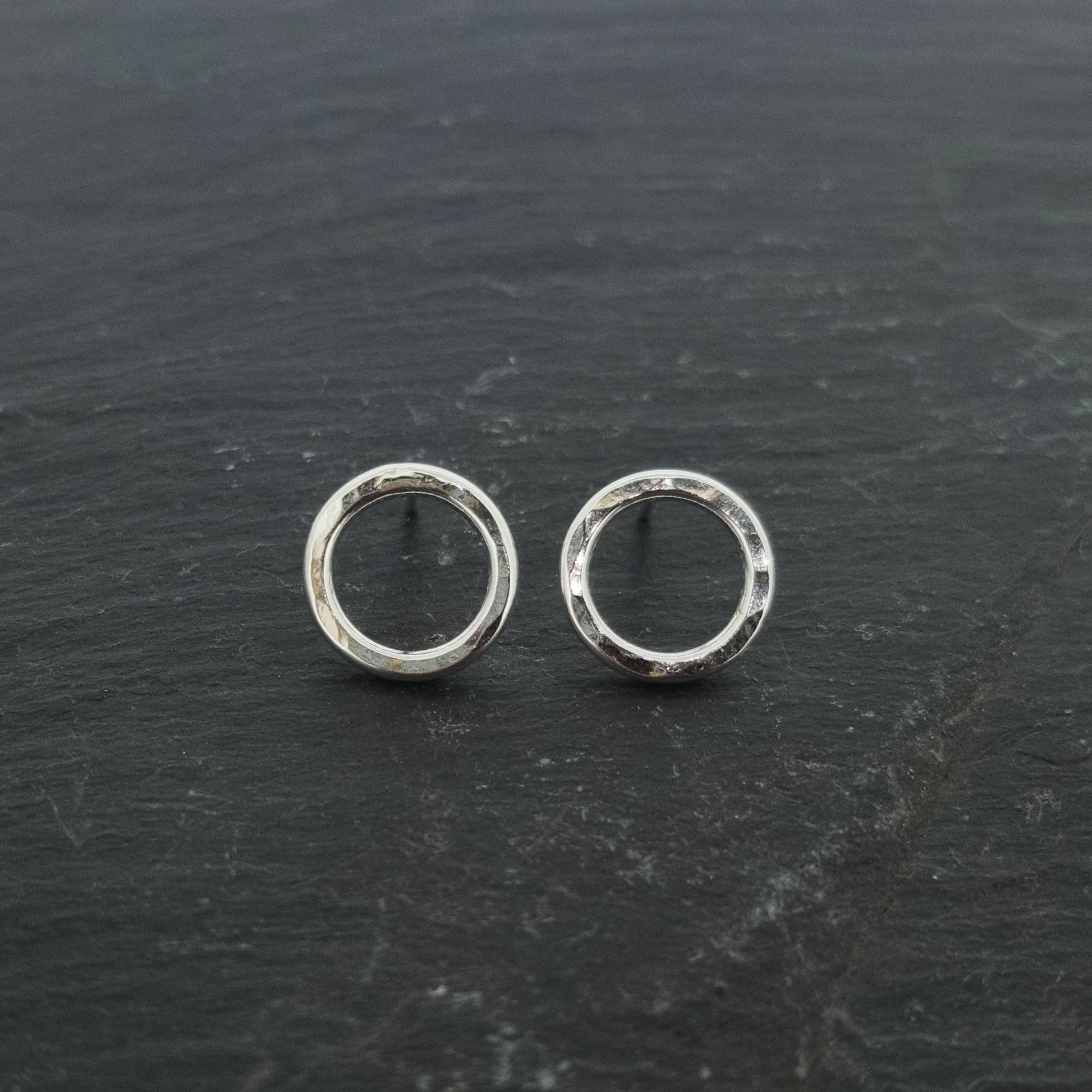 Silver open circle stud earrings with hammered texture.